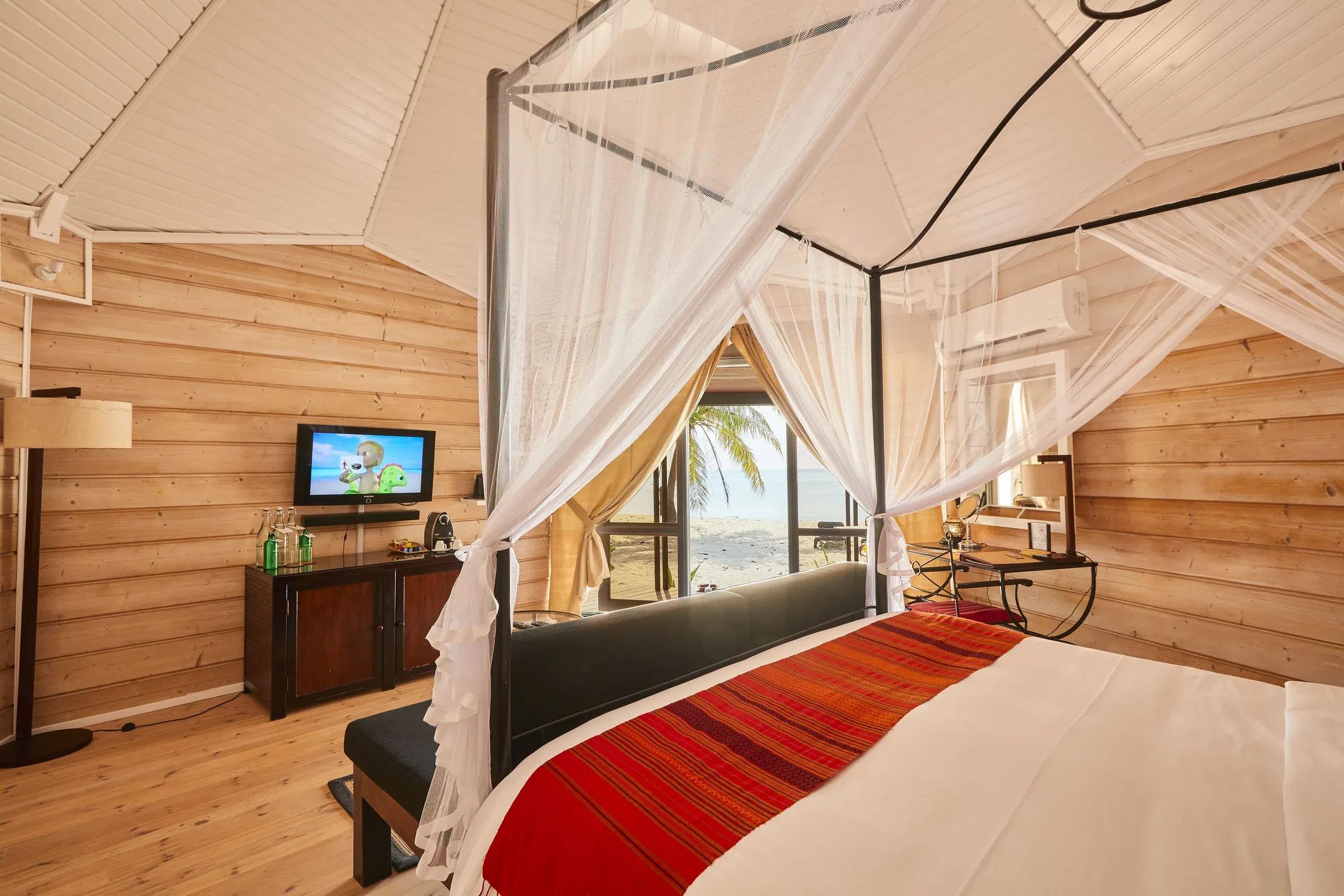 Camera Premium Beach Villa con letto a baldacchino e vista sulla spiaggia al Kuredu Island Resort & Spa.