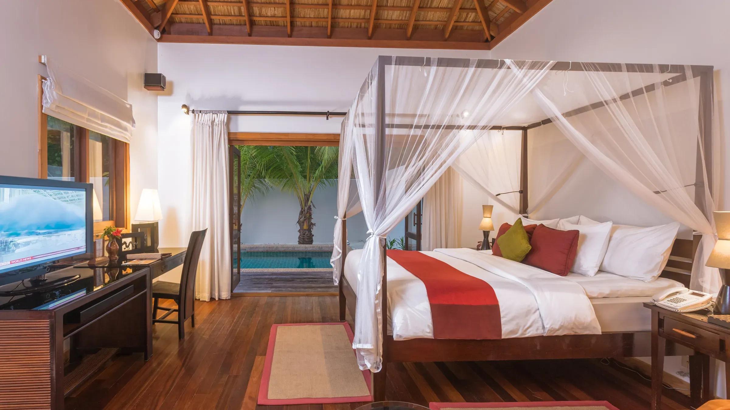 Camera da letto della Private Pool Villa con letto a baldacchino e vista sulla piscina al Kuredu Island Resort & Spa