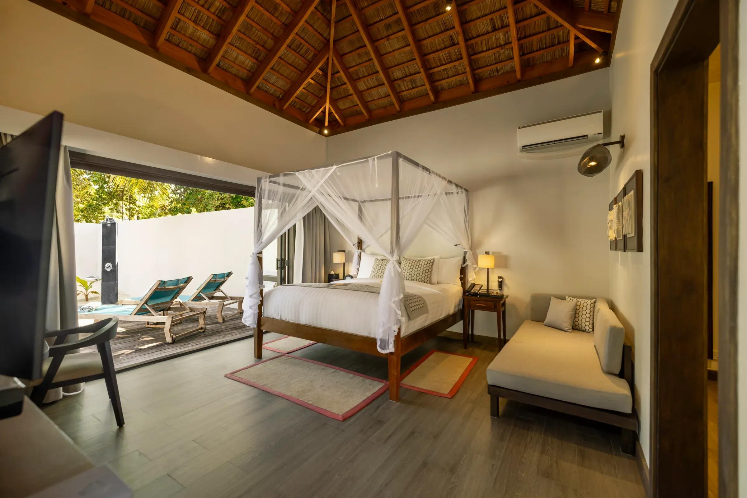 Camera da letto della Private Pool Villa Family Suite con letto a baldacchino e accesso alla piscina del Kuredu Island Resort & Spa.