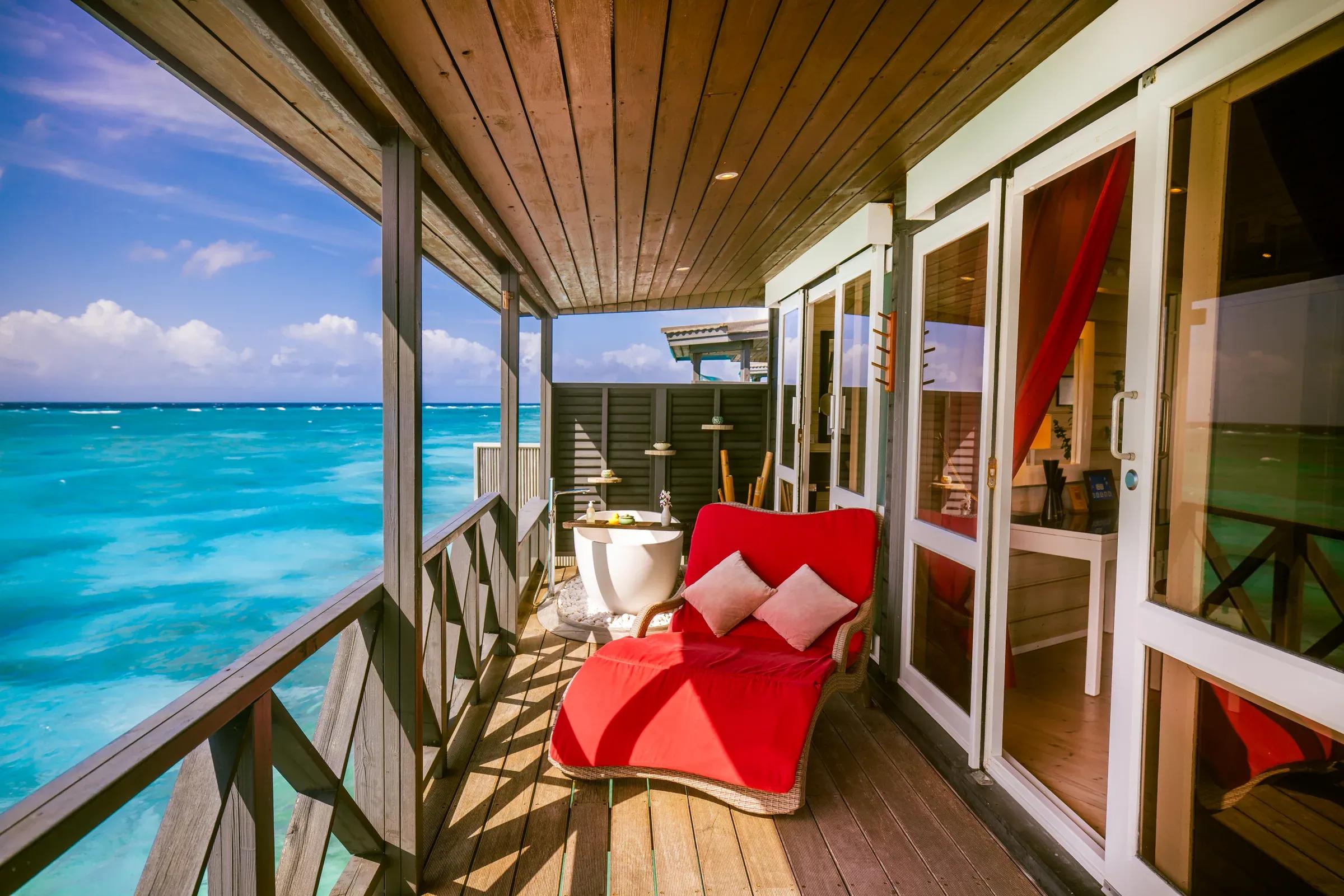 Terrazza della Sangu Water Villa Honeymoon Suite con lettino rosso e vista oceano al Kuredu Island Resort & Spa.