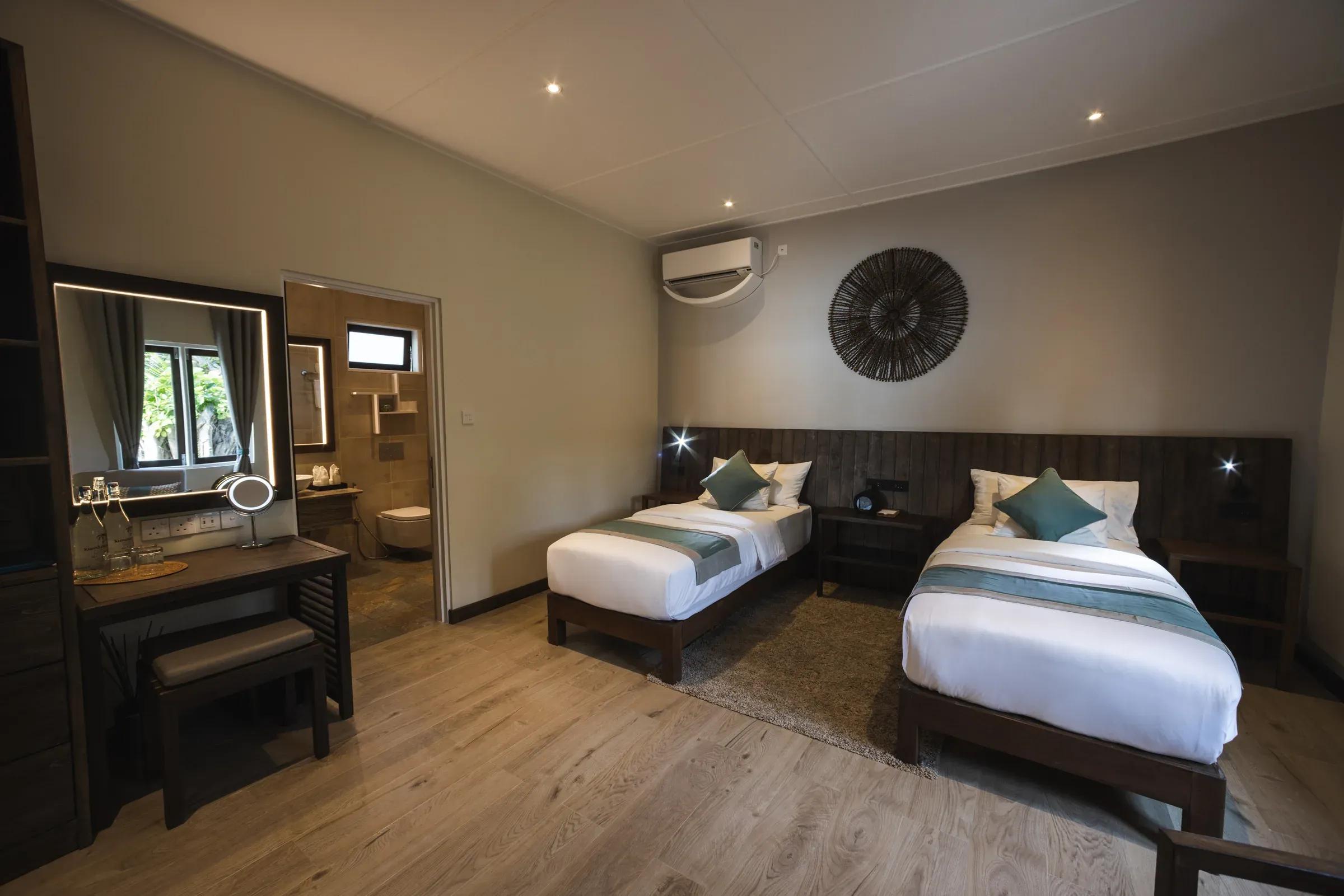 Interno della Two Bedroom Beach Villa con letti singoli e scrivania al Kuredu Island Resort & Spa.