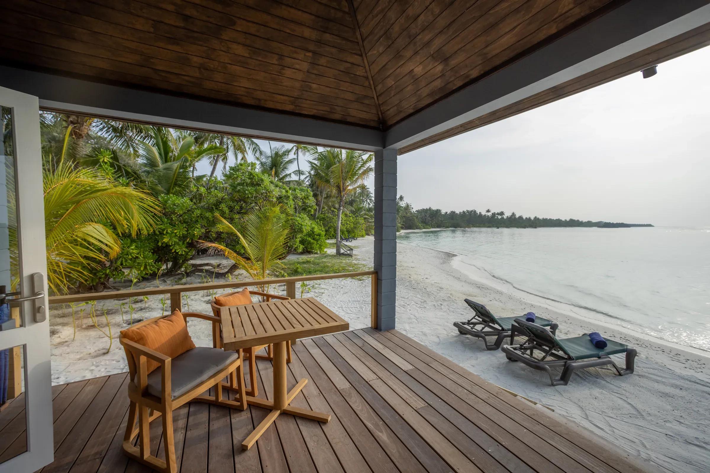 Terrazza della Two Bedroom Beach Villa con sedie in legno e vista sulla spiaggia del Kuredu Island Resort & Spa
