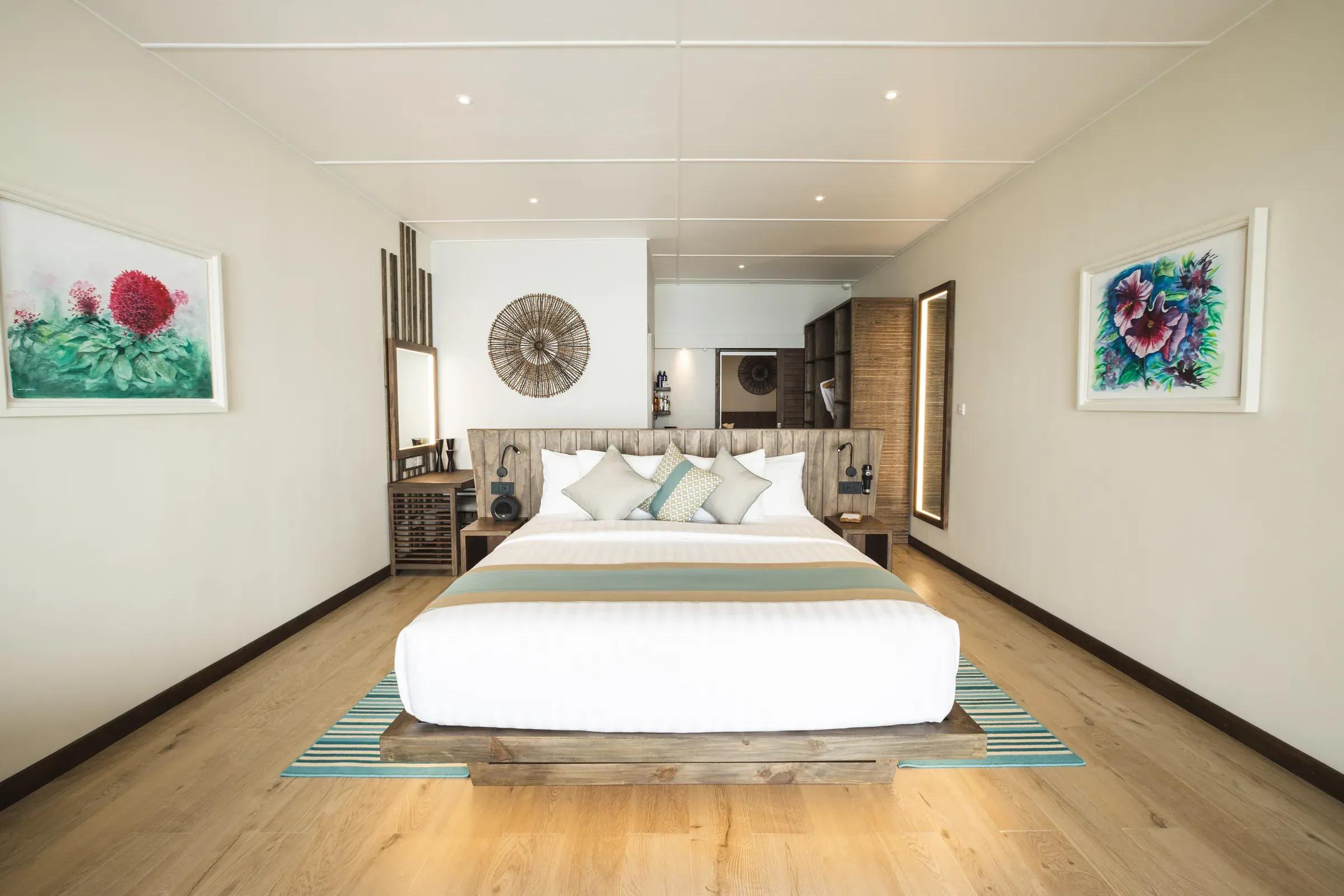 Camera da letto della Two Bedroom Beach Villa con letto matrimoniale e decorazioni artistiche al Kuredu Island Resort & Spa.