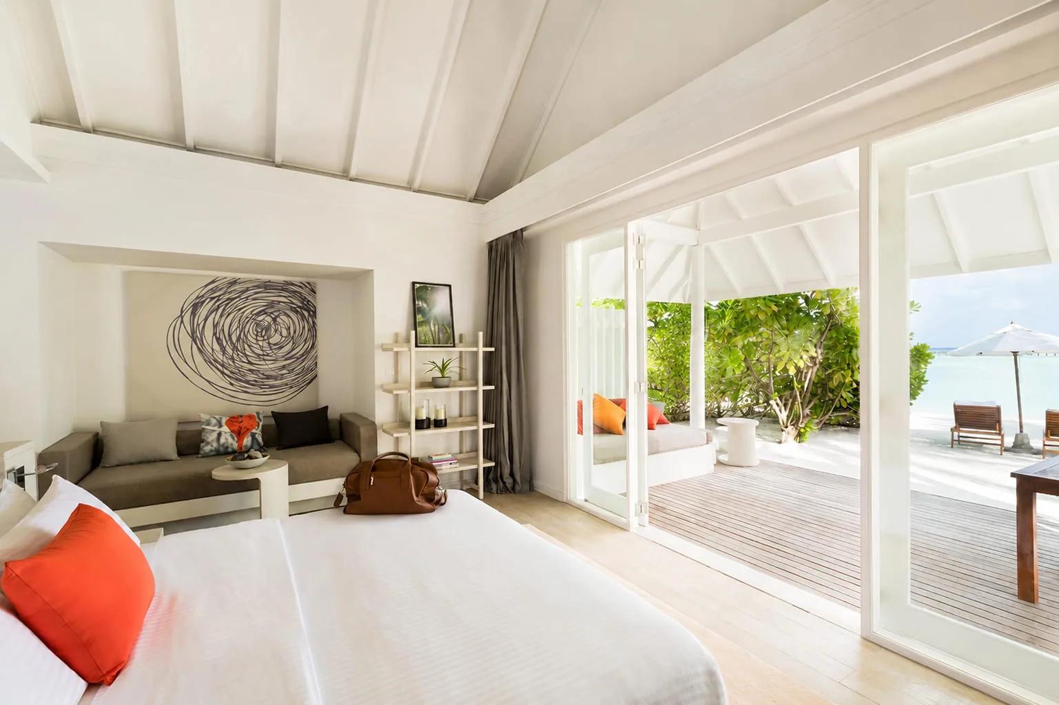 Interno della Beach Villa con letto matrimoniale e terrazza vista mare al LUX* South Ari Atoll.