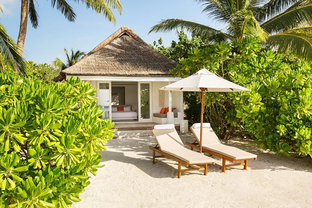 Veduta della Beach Villa con lettini prendisole sulla sabbia e vegetazione al LUX* South Ari Atoll.