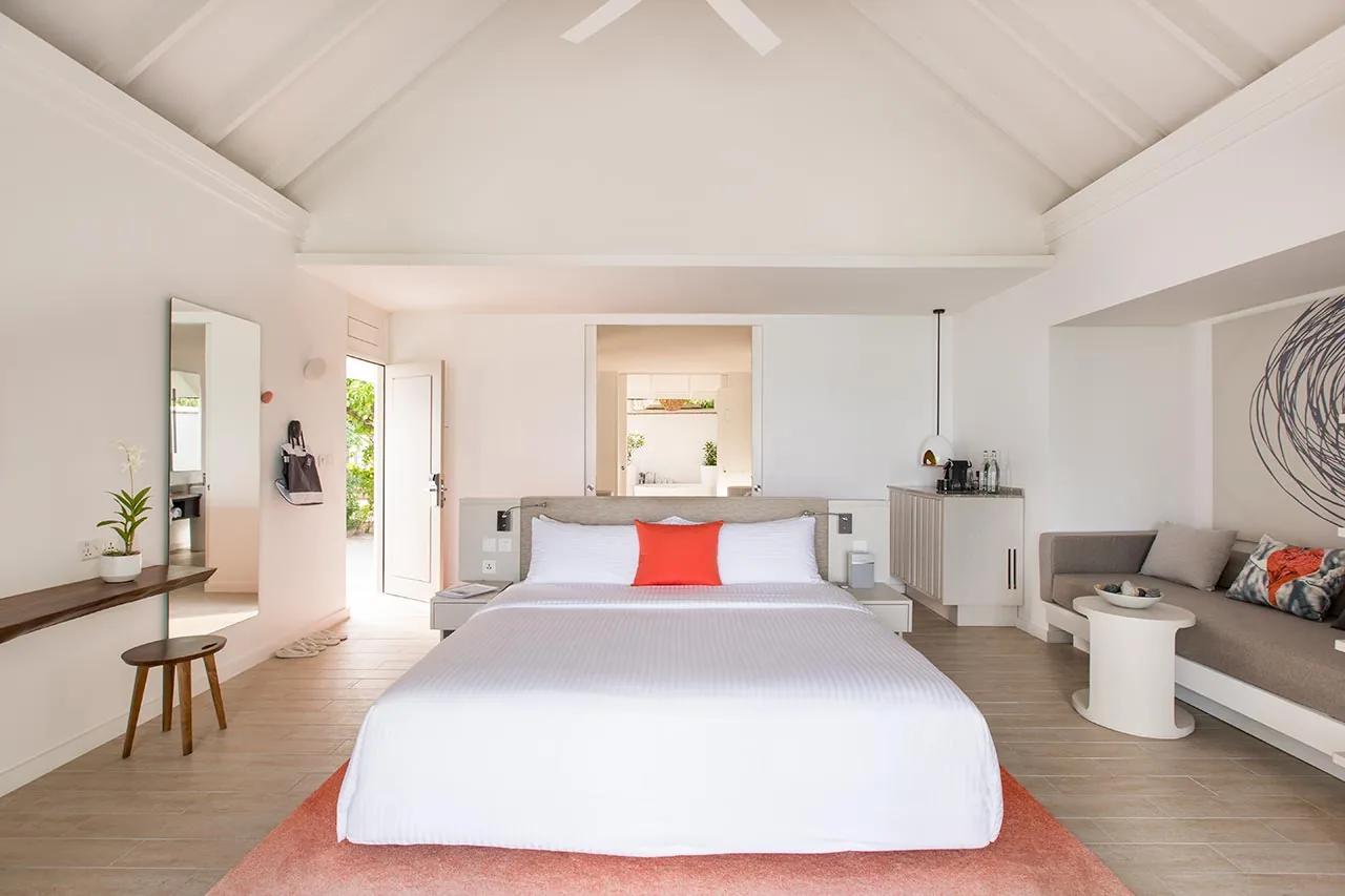 Interno della Beach Villa con letto matrimoniale e divano nel LUX* South Ari Atoll.