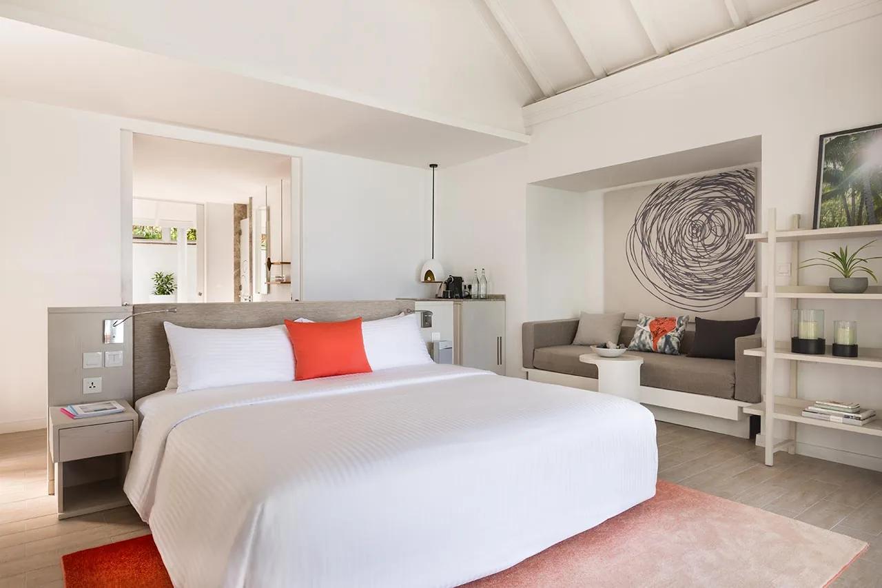Interno della Beachfront Infinity Pool Villa con letto matrimoniale e area salotto al LUX* South Ari Atoll.
