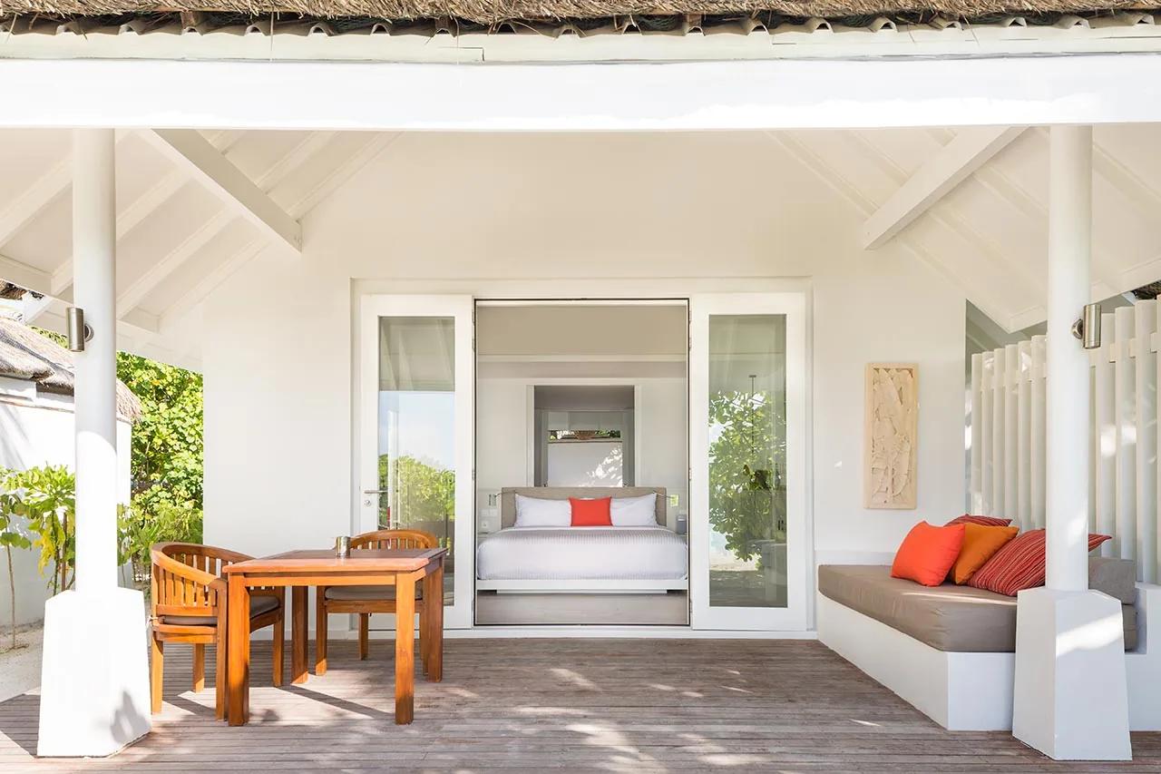 Terrazza della Beachfront Infinity Pool Villa con tavolo in legno e divano, LUX* South Ari Atoll.
