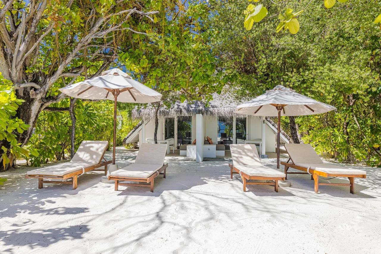 Terrazza della Family Beach Pavilion con lettini e ombrelloni sulla sabbia presso LUX* South Ari Atoll.