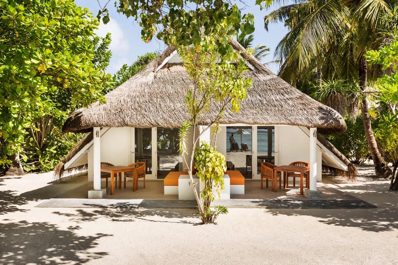 Veranda della Family Beach Pavilion con tavoli esterni e accesso alla spiaggia del LUX* South Ari Atoll.