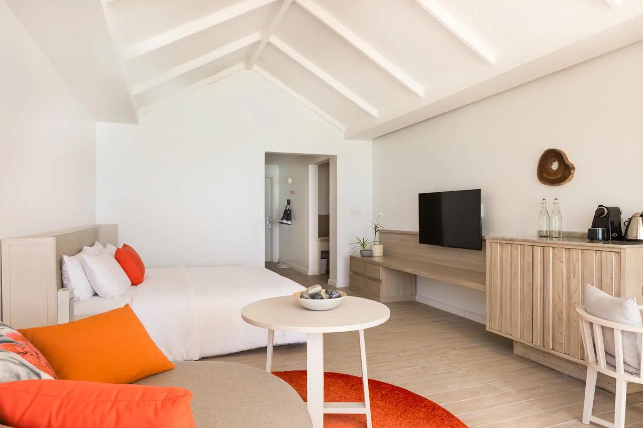 Interno della Family Lagoon Pavilion con letto matrimoniale, divano e TV al LUX* South Ari Atoll.