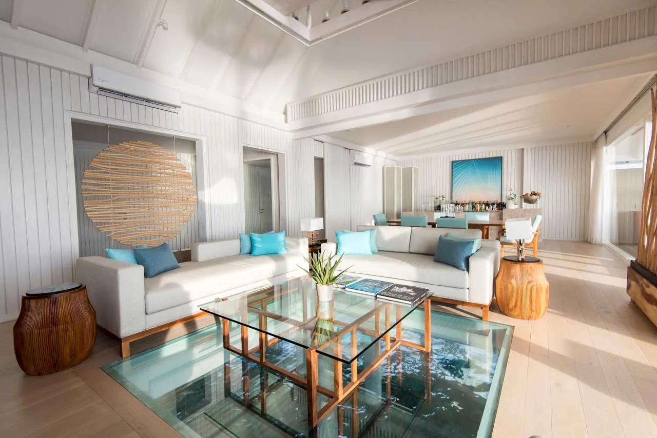 Soggiorno della Lux* Villa con tavolino in vetro e zona relax al LUX* South Ari Atoll.