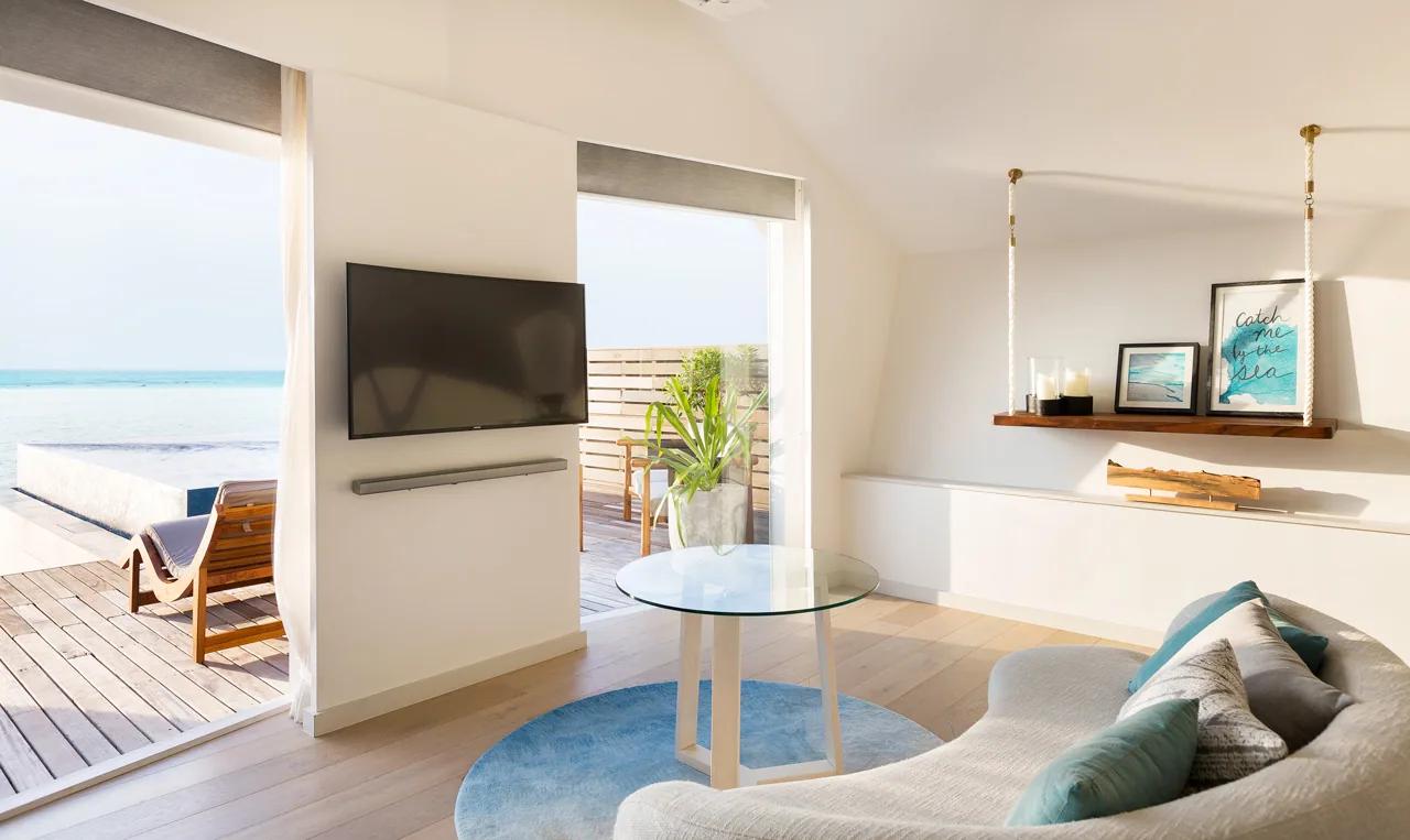 Salotto della Overwater Infinity Pool Villa con TV a schermo piatto e terrazza vista mare al LUX* South Ari Atoll
