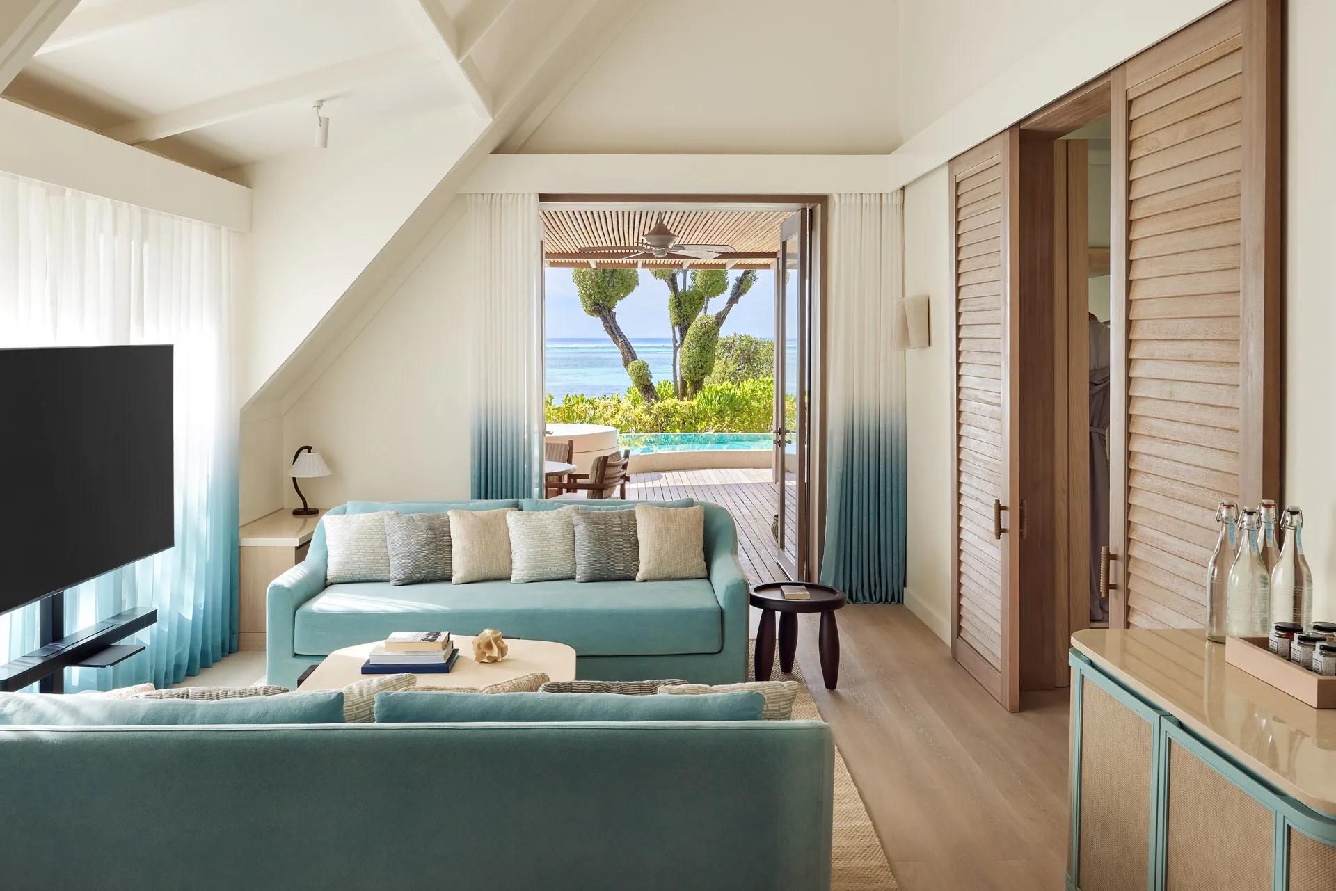 Interno della Temptation Beach Pool Villa con divani, tavolo e vista mare al LUX* South Ari Atoll.