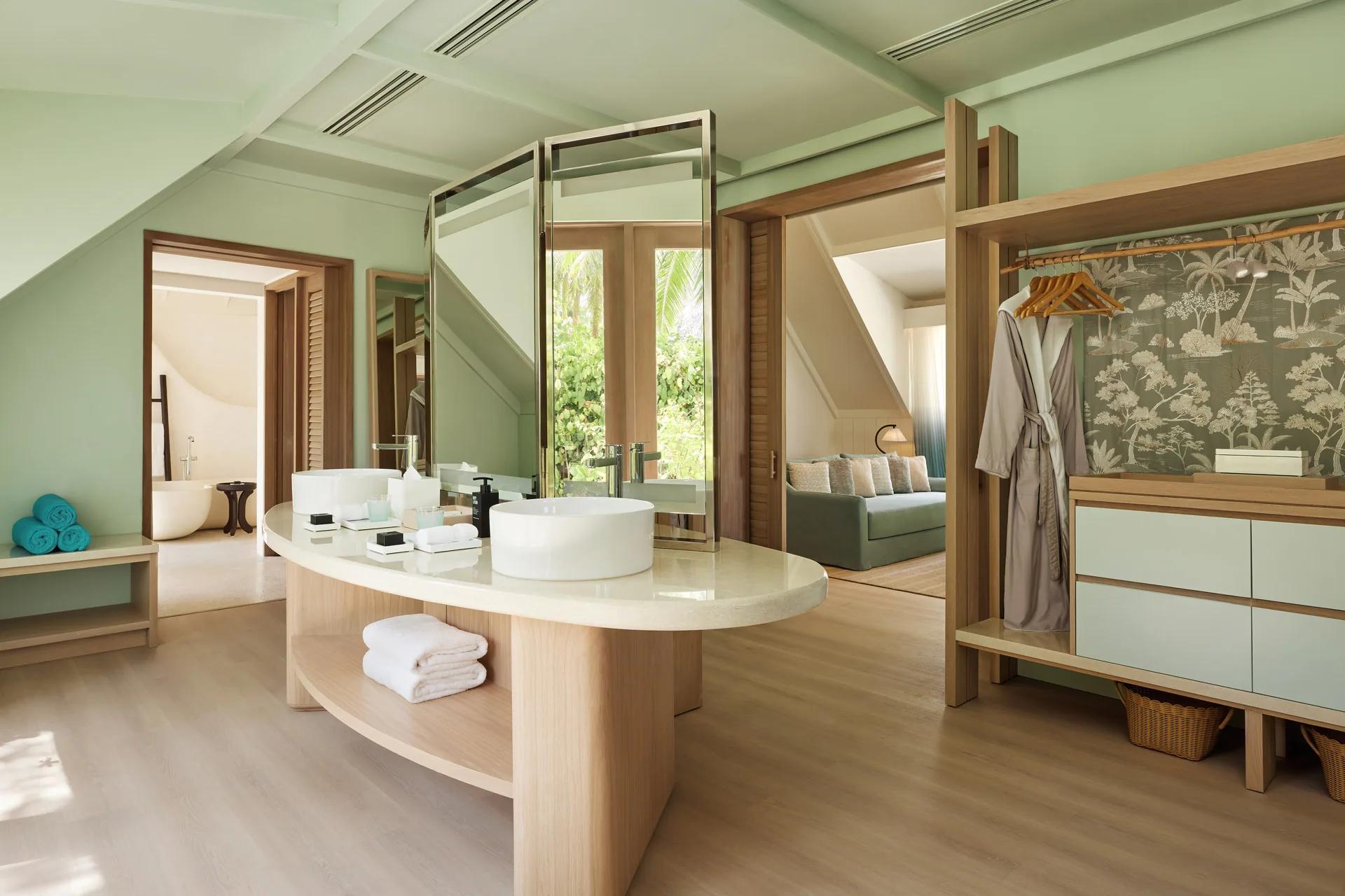 Interno della Temptation Beach Pool Villa con lavabo, specchi e divano al LUX* South Ari Atoll.