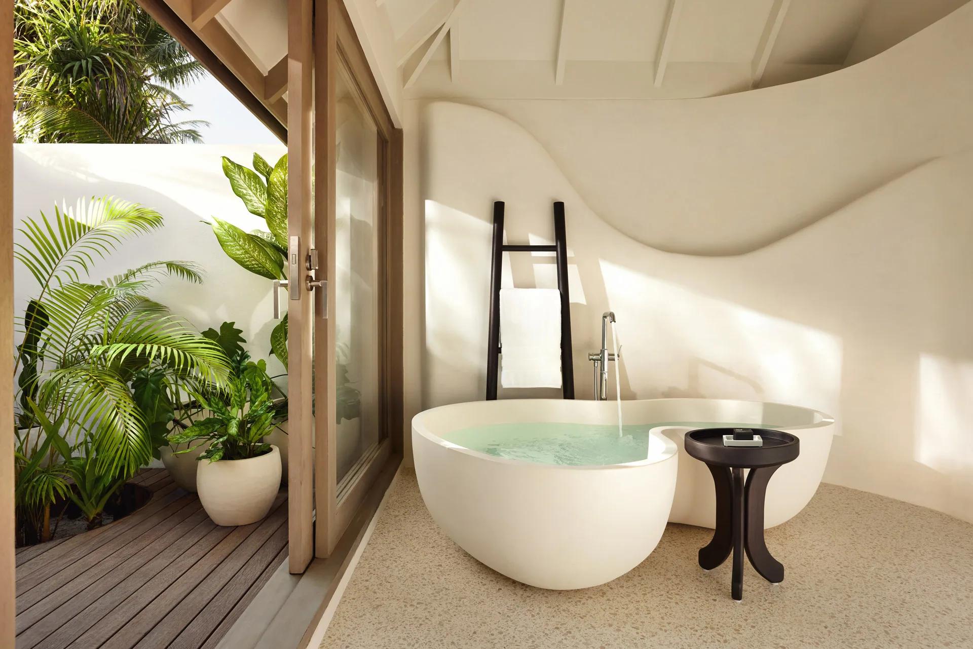 Interno della Temptation Beach Pool Villa con vasca da bagno e piante tropicali al LUX* South Ari Atoll.