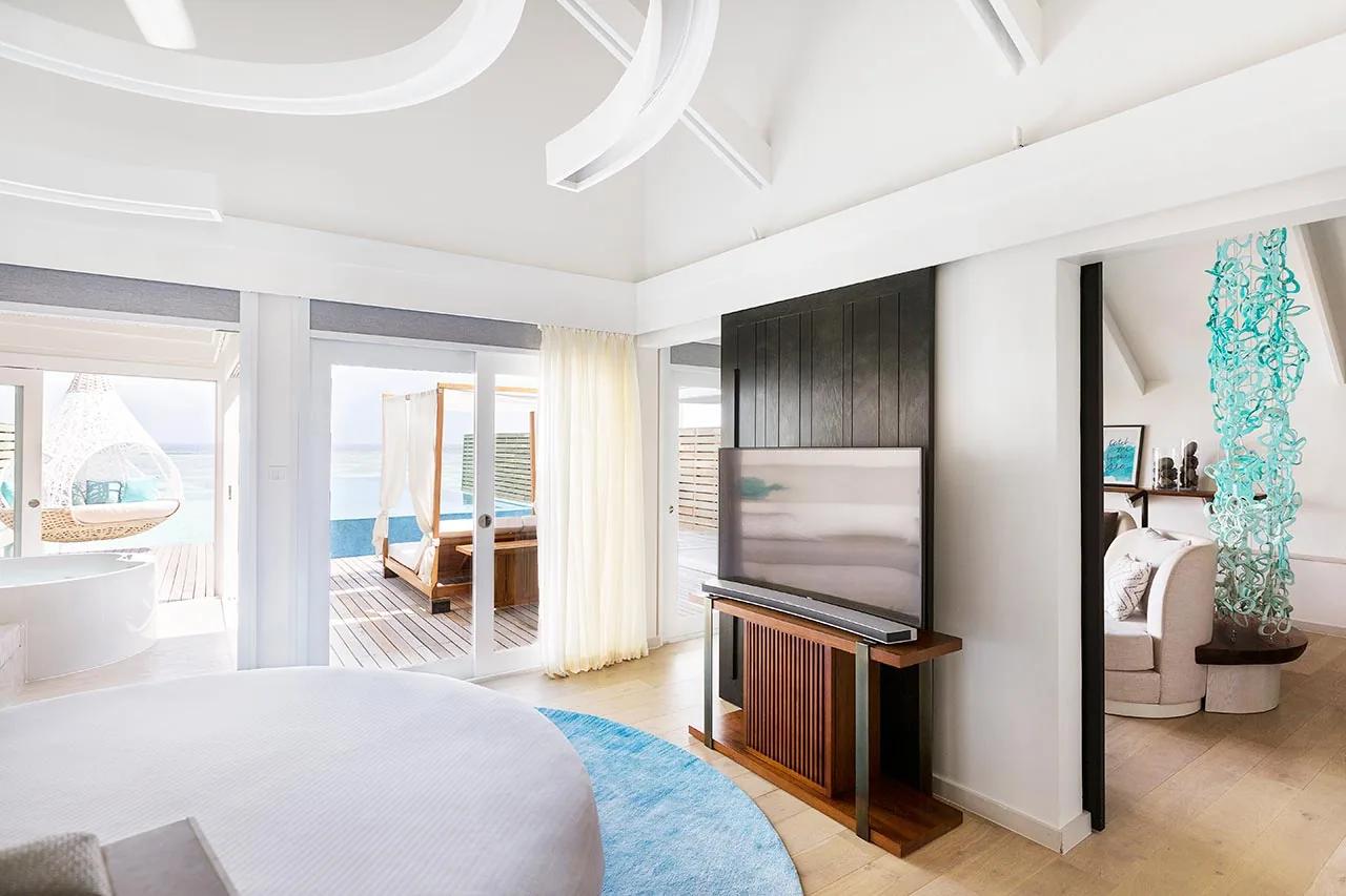 Interno della Temptation Pool Water Villa con letto rotondo e vista sulla terrazza del LUX* South Ari Atoll.