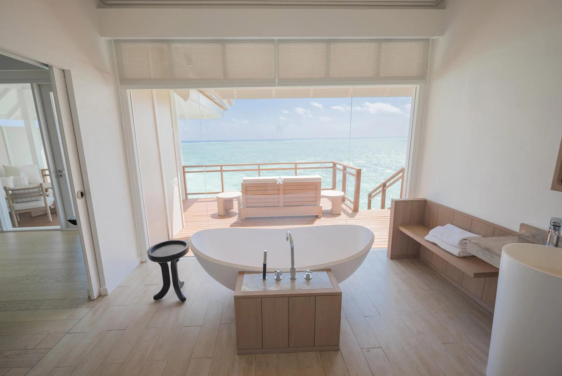 Interno della Water Villa con vasca e terrazza vista mare al LUX* South Ari Atoll.