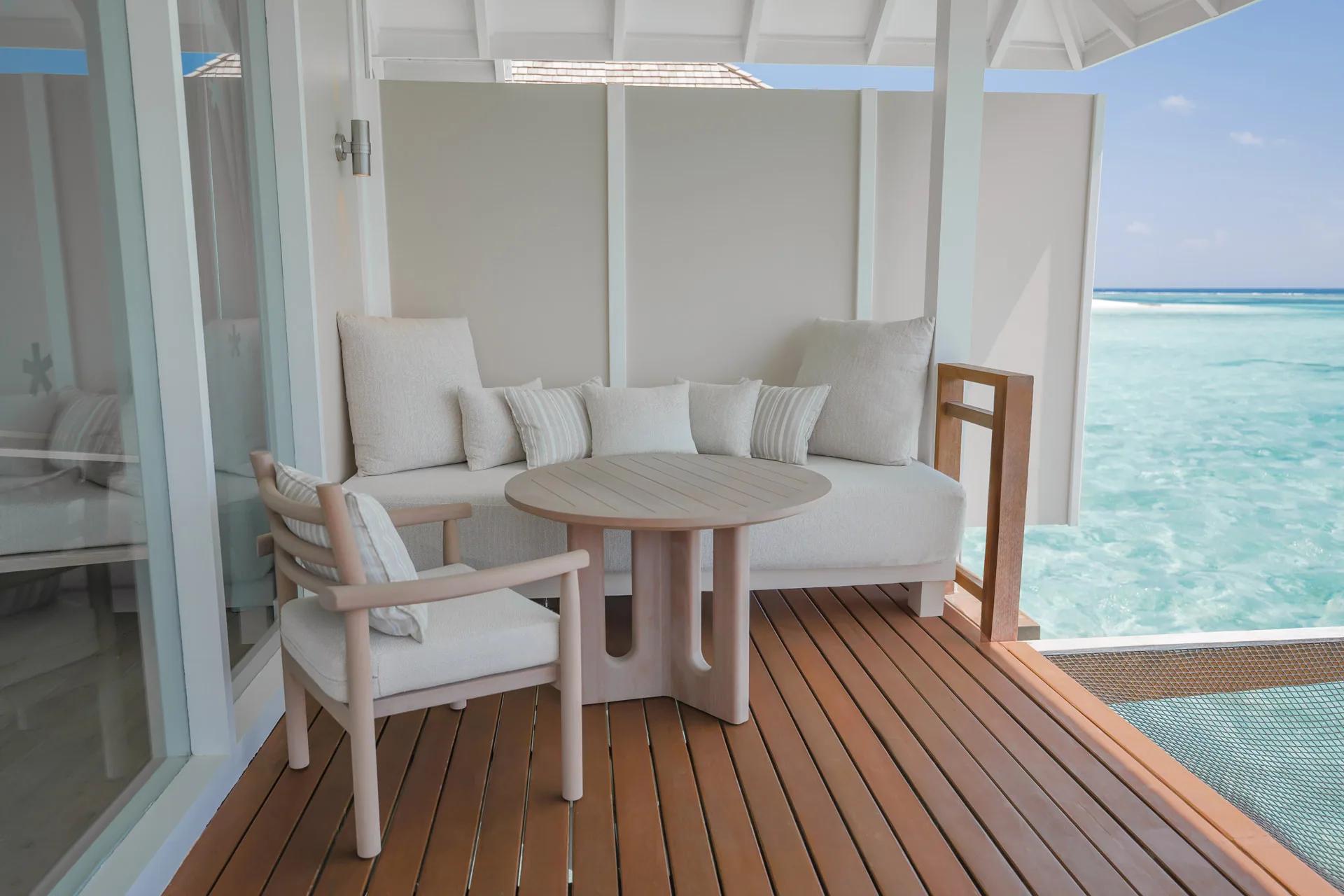 Terrazza della Water Villa con seduta in legno e vista sull'oceano al LUX* South Ari Atoll.
