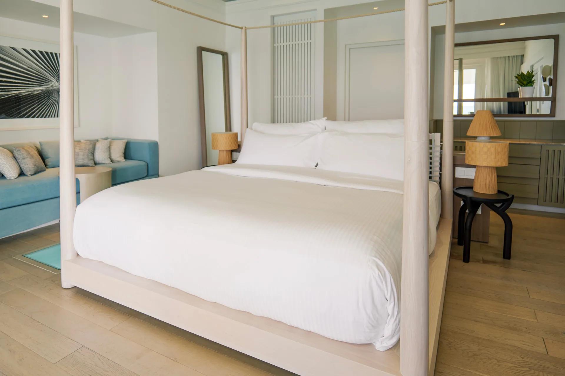 Interno della Water Villa con letto a baldacchino e divano al LUX* South Ari Atoll