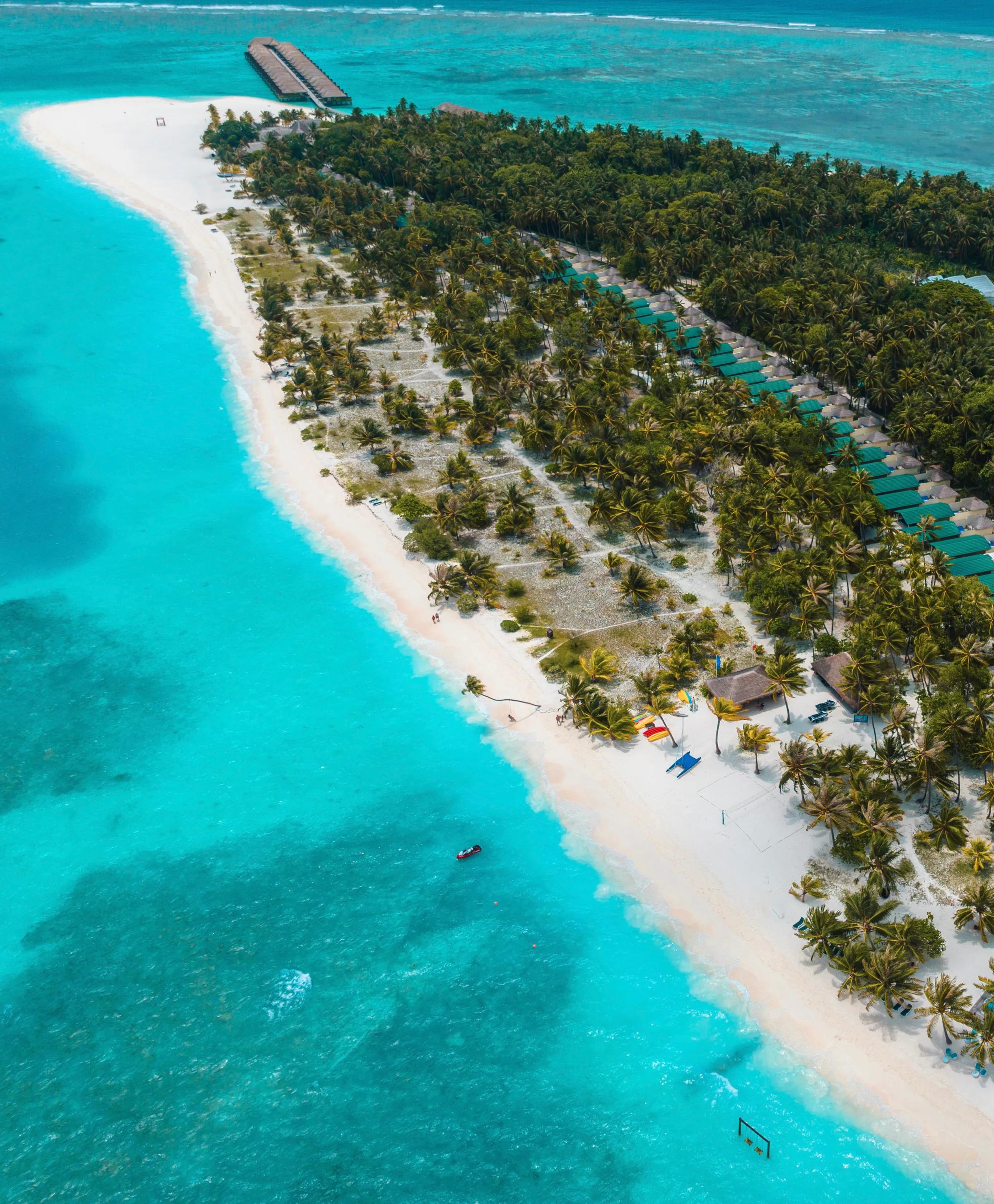 Spiaggia con palme e mare turchese al Meeru Island Resort & Spa.