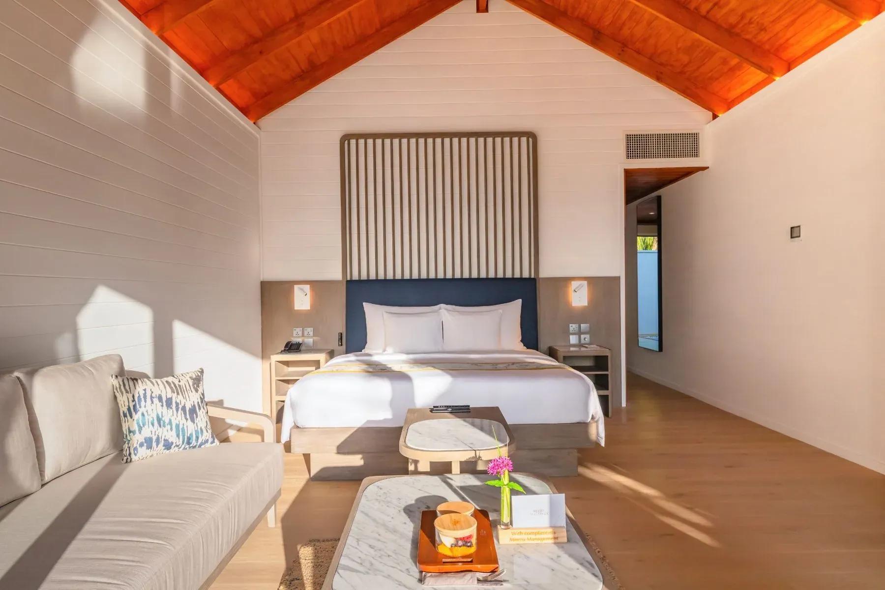 Interno della Beach Pool Villa con letto matrimoniale e divano al Meeru Island Resort & Spa.
