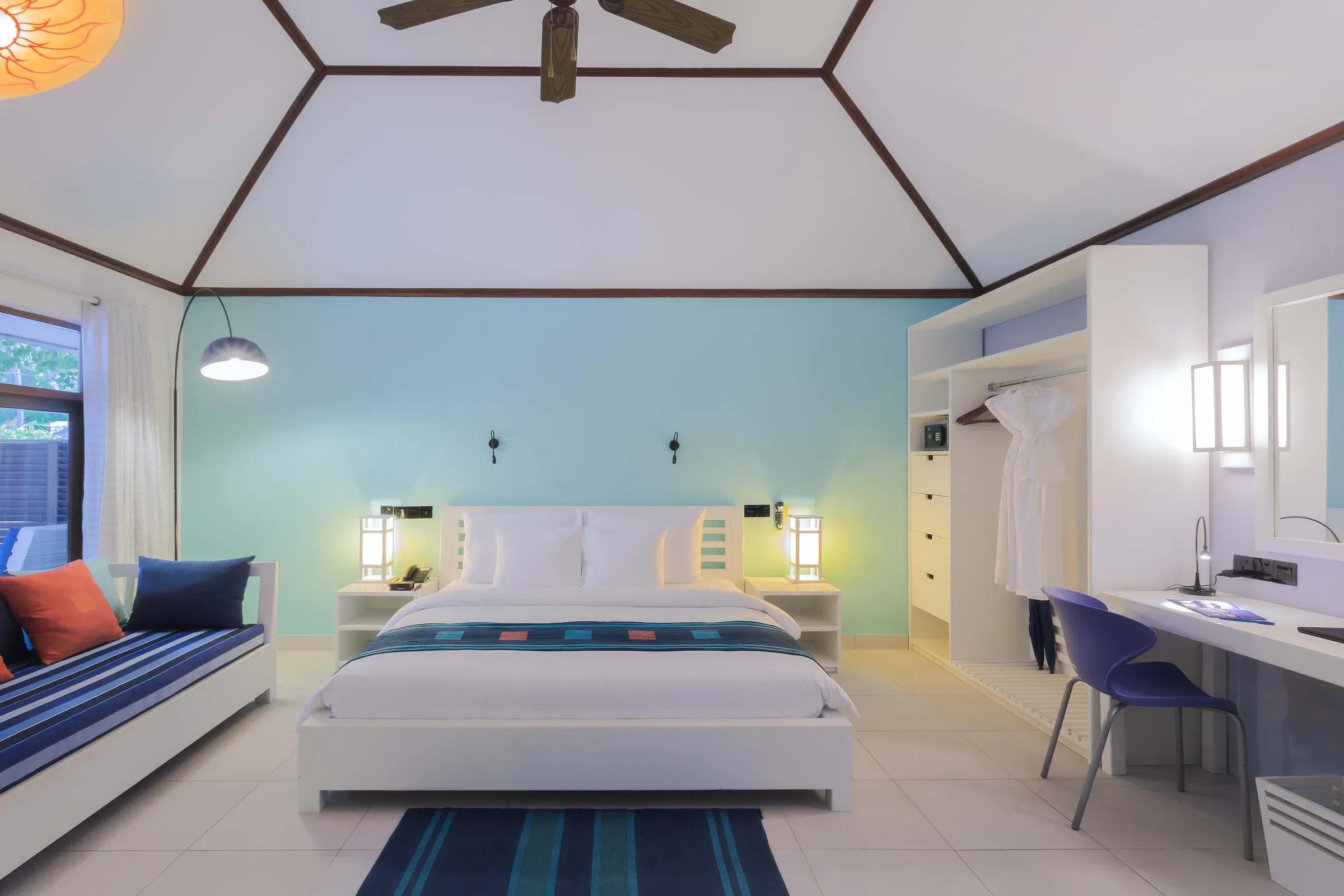 Camera Garden Room con letto matrimoniale e zona relax al Meeru Island Resort & Spa.