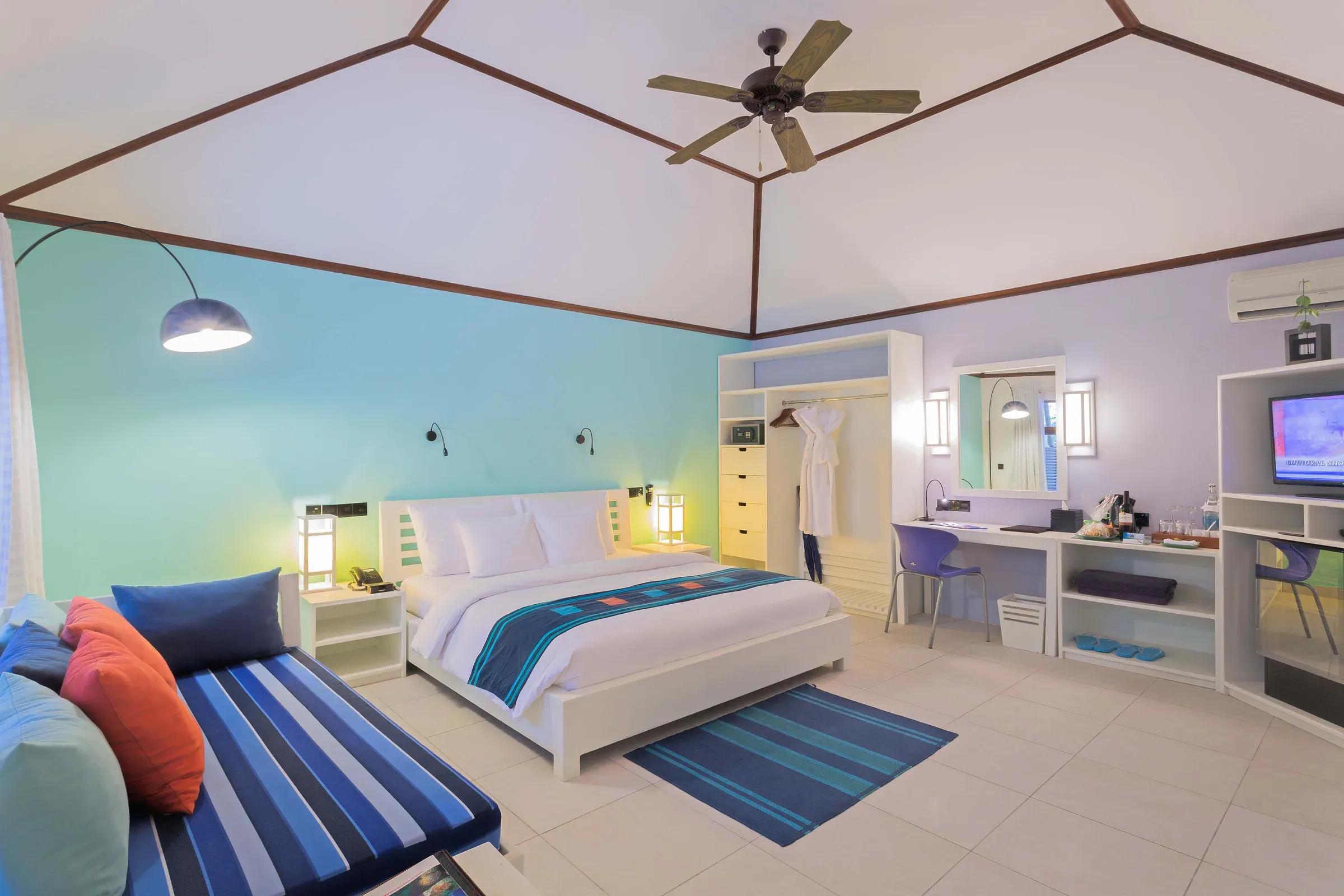 Camera Garden Room con letto matrimoniale e area relax al Meeru Island Resort & Spa.