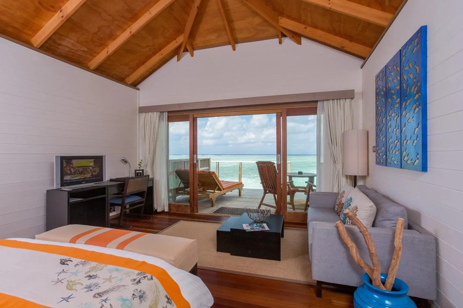 Interno della Jacuzzi Water Villa con letto, divano e terrazza con vista mare al Meeru Island Resort & Spa.