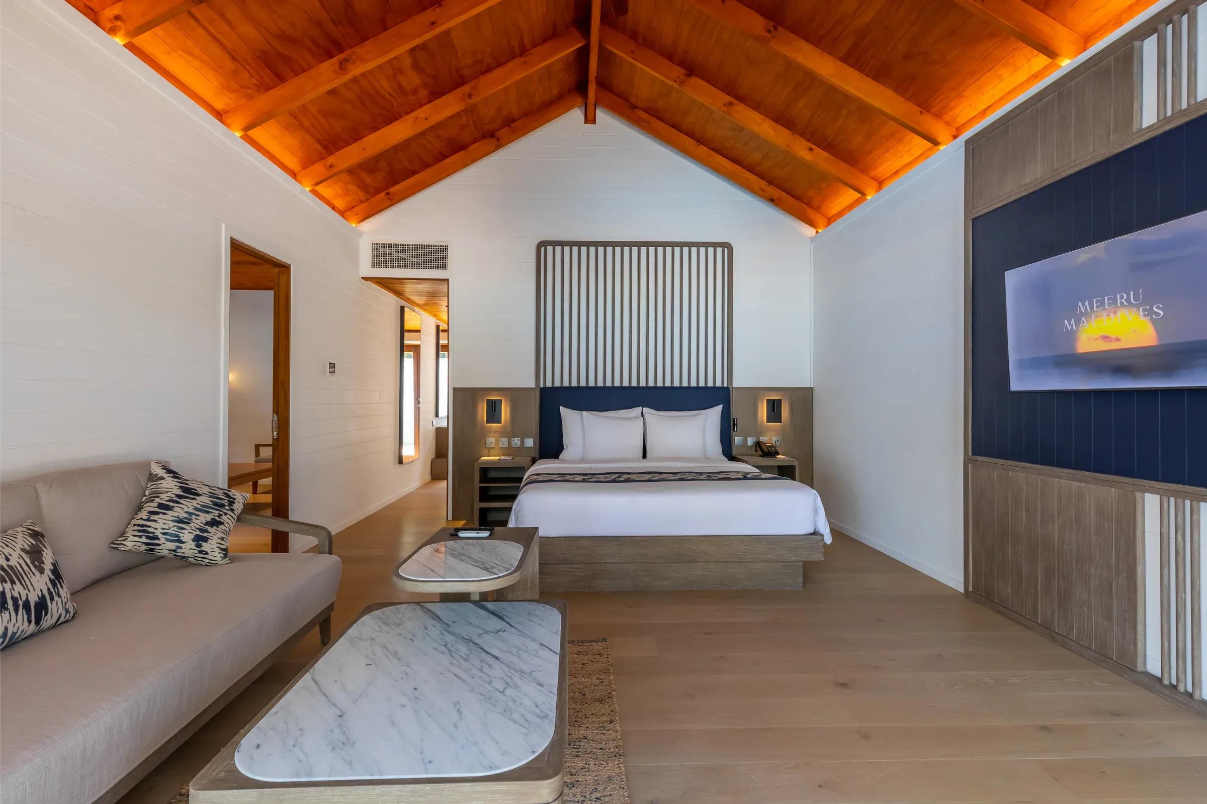 Interno della Two Bedroom Beach Pool Villa con letto matrimoniale e divano, Meeru Island Resort & Spa.