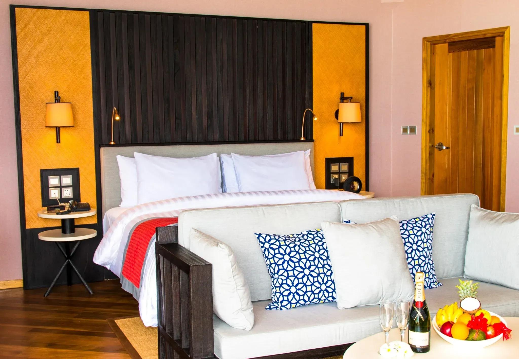 Water Front Villa con letto matrimoniale, cuscini colorati e tavolino al Meeru Island Resort & Spa.