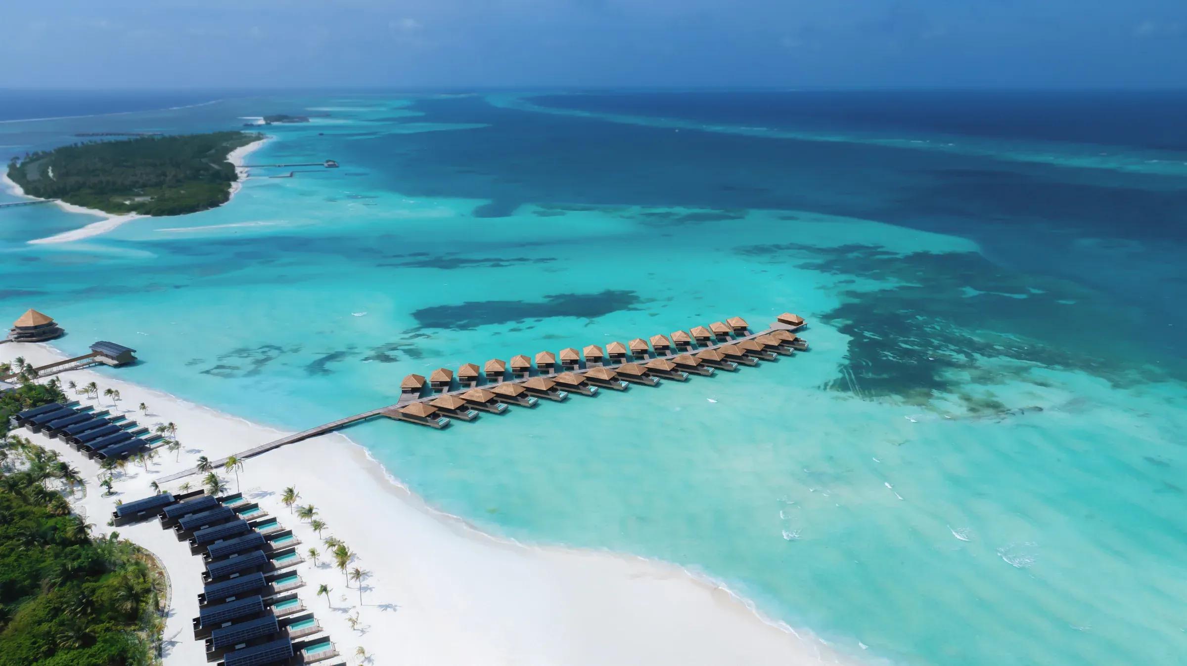 Vista aerea del resort Nala Maldives By Jawakara con ville sull'acqua e spiaggia bianca.