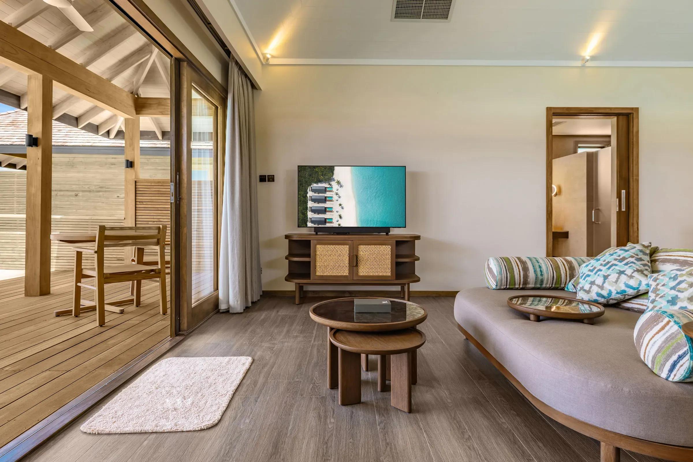 Soggiorno della Ocean Pool Villa con divano, TV e tavolino al Nala Maldives By Jawakara.