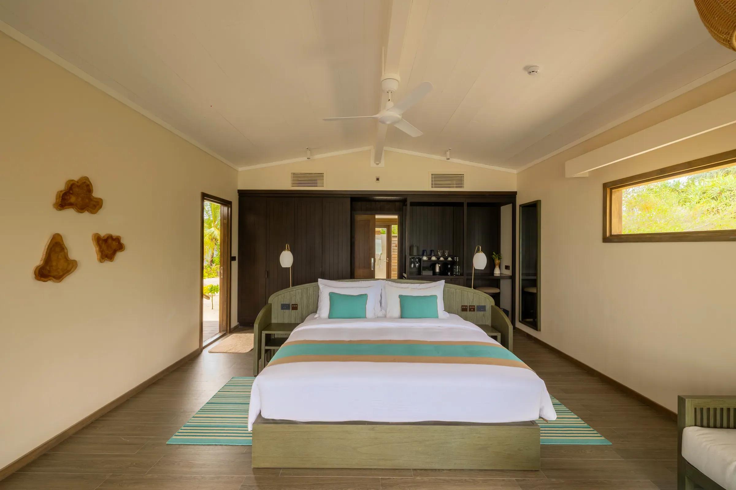 Camera da letto con letto matrimoniale e ventilatore a soffitto nella Sunrise Beach Villa al Nala Maldives By Jawakara.