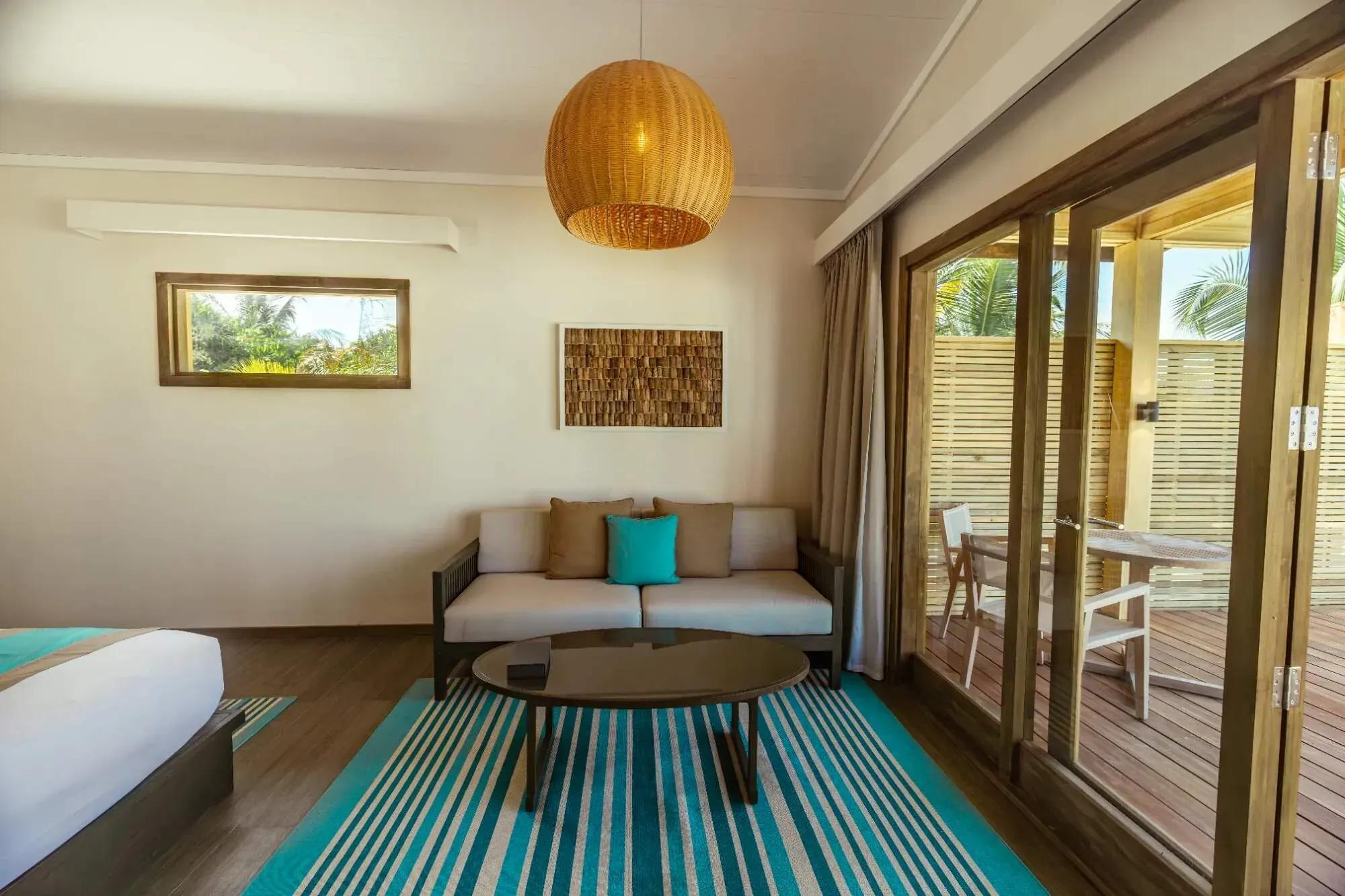 Interno della Sunset Beach Pool Villa con divano e area esterna al Nala Maldives By Jawakara.