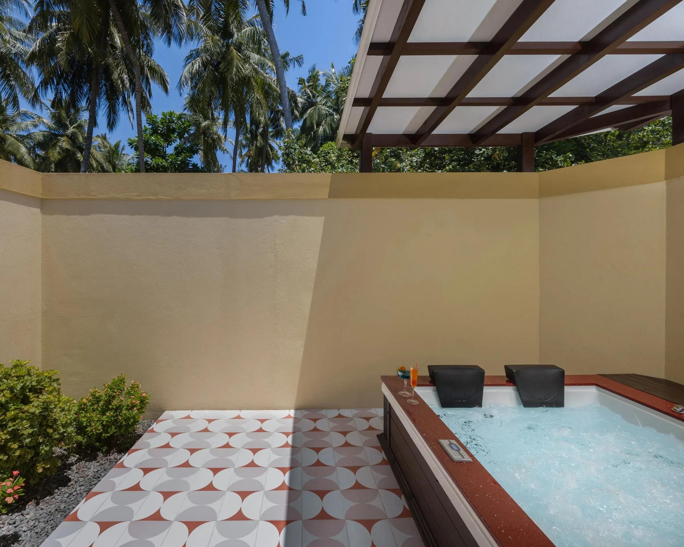 Vasca idromassaggio e pavimento geometrico nella Beach Pool Villa del Royal Island Resort & Spa con palme tropicali
