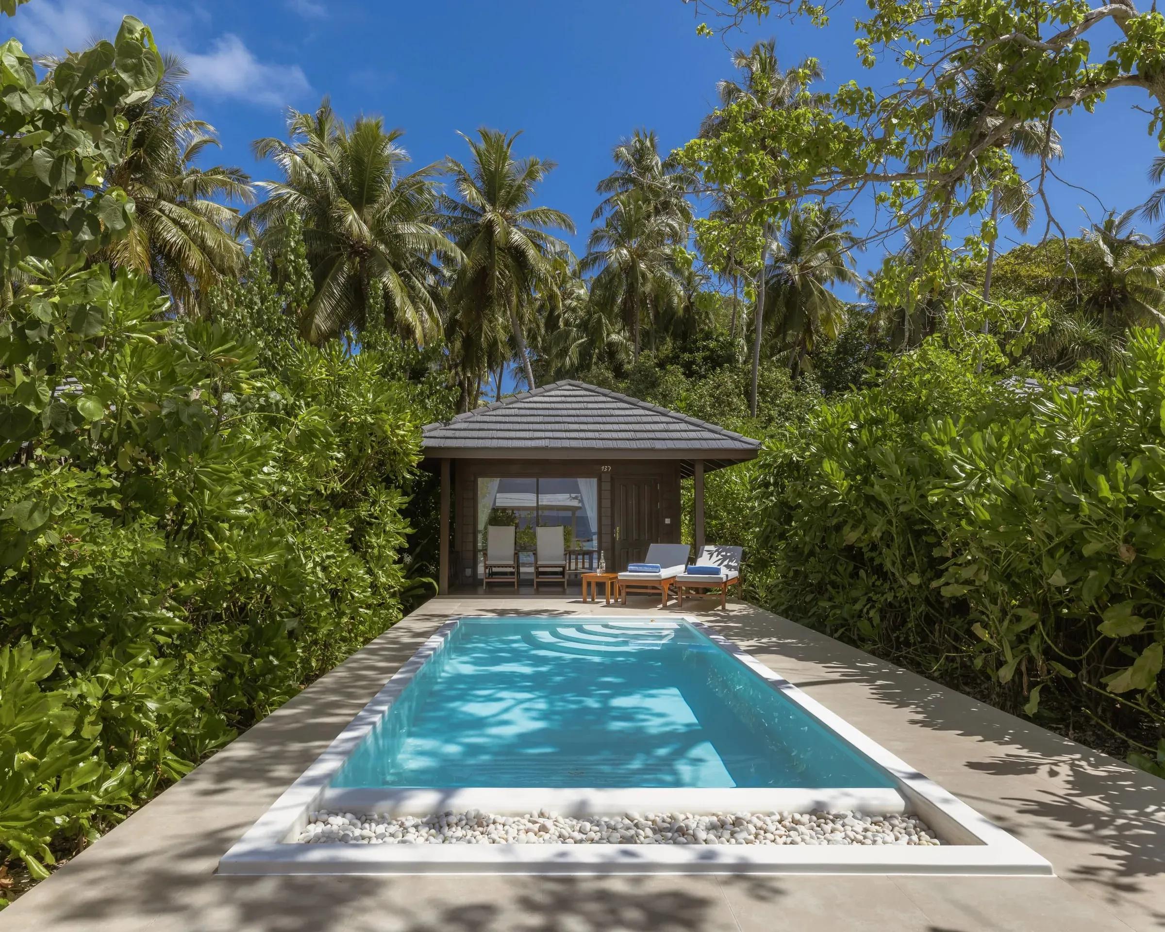 Piscina privata e villa con tetto in legno circondata da palme nella Beach Pool Villa del Royal Island Resort & Spa