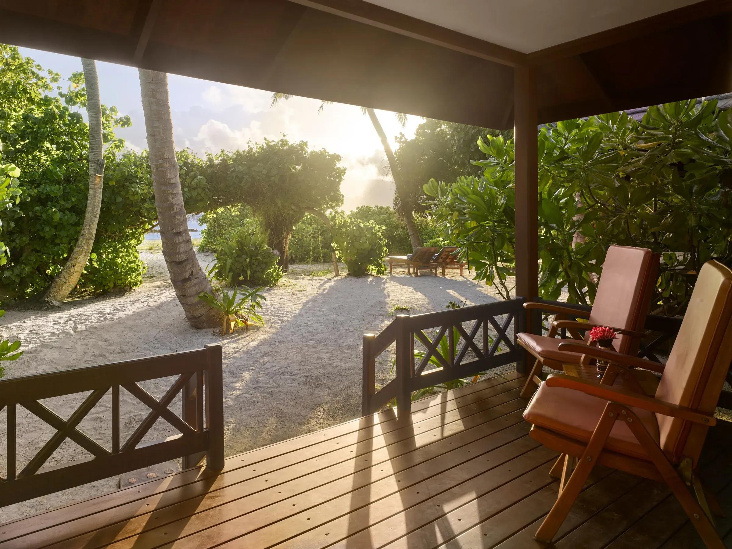 Terrazza in legno con sedie e vista sulla spiaggia con palme della Sunset Beach Villa al Royal Island Resort & Spa