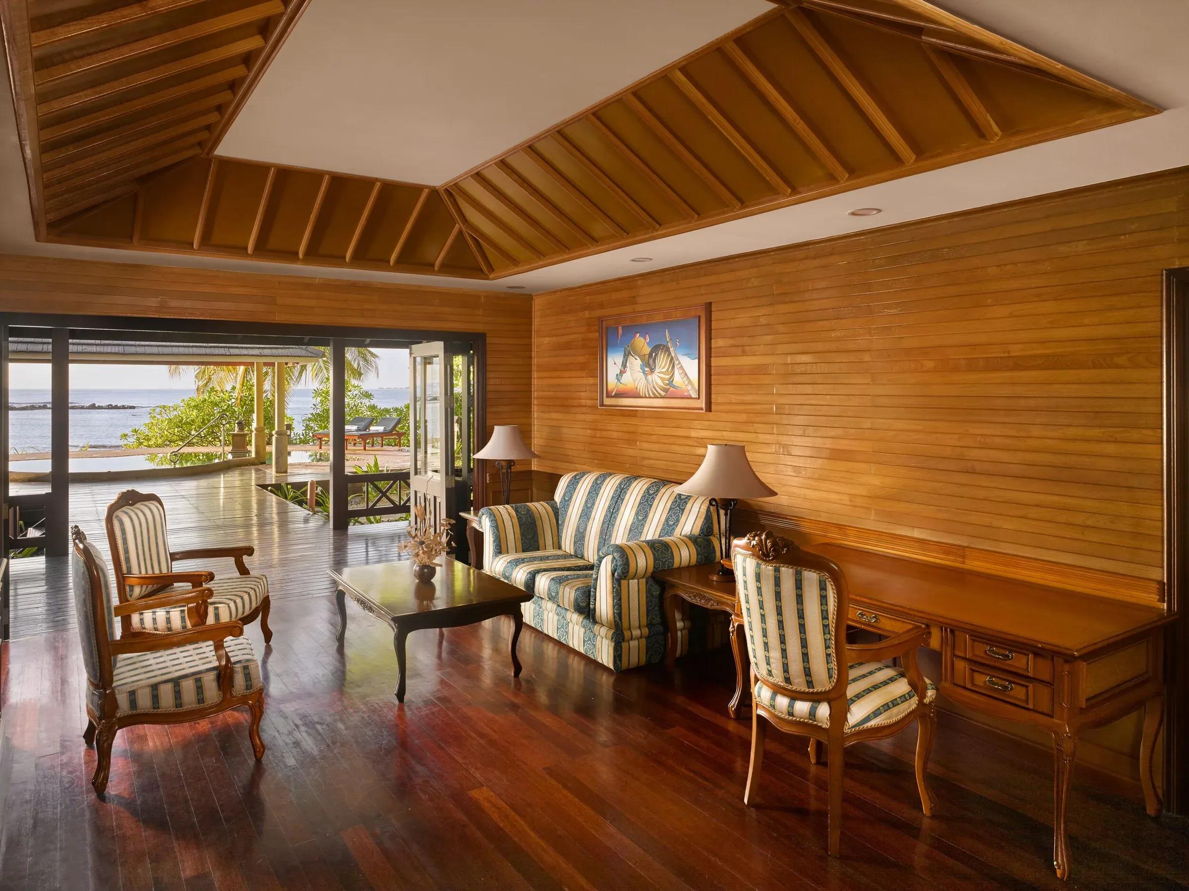 Soggiorno con divano a righe e terrazza vista mare della Two Bedroom Beach Pool Residence al Royal Island Resort & Spa