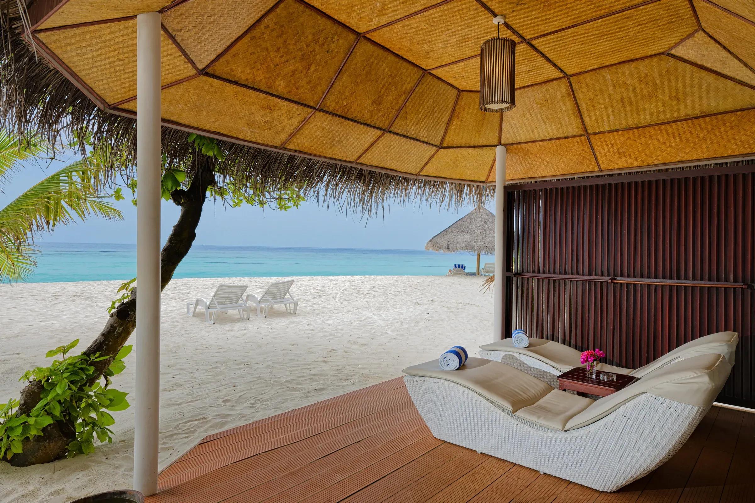 Terrazza della Beach Bungalow con lettini e vista sulla spiaggia al Thulhagiri Island Resort & Spa.