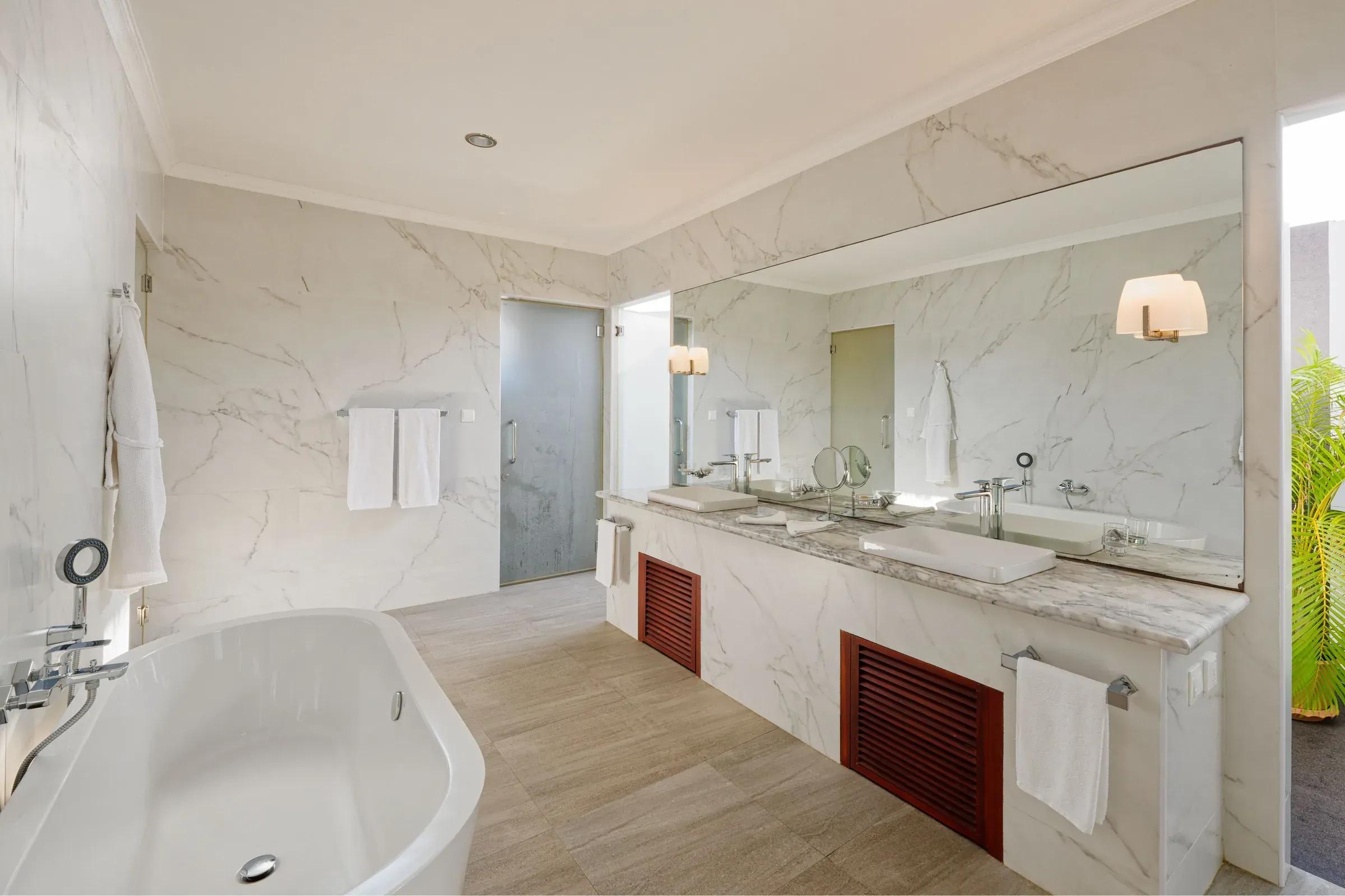 Bagno della Superior Water Bungalow con vasca e doppio lavabo al Thulhagiri Island Resort & Spa.