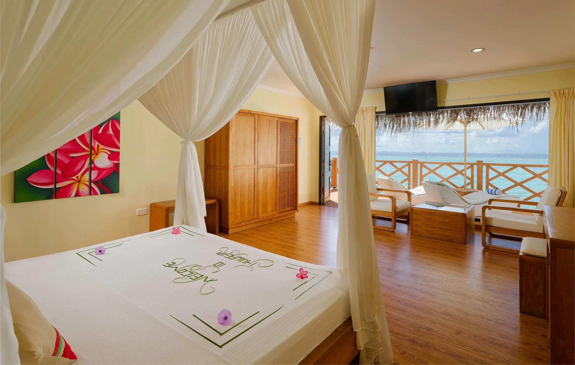 Camera Superior Water Bungalow con letto a baldacchino e terrazza vista mare al Thulhagiri Island Resort & Spa.