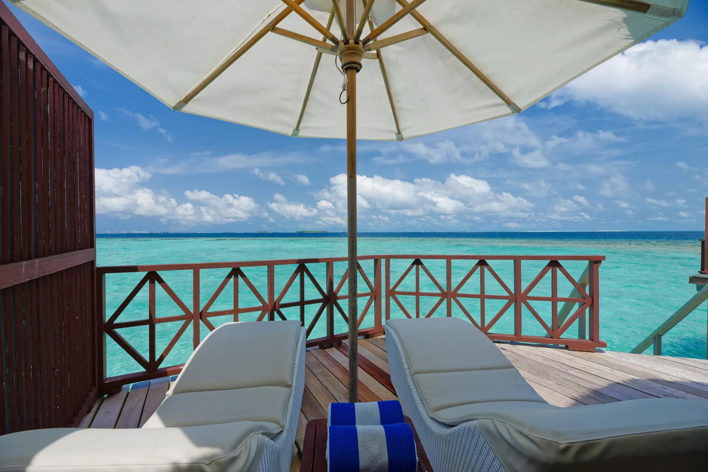 Terrazza della Water Bungalow con lettini e ombrellone al Thulhagiri Island Resort & Spa.