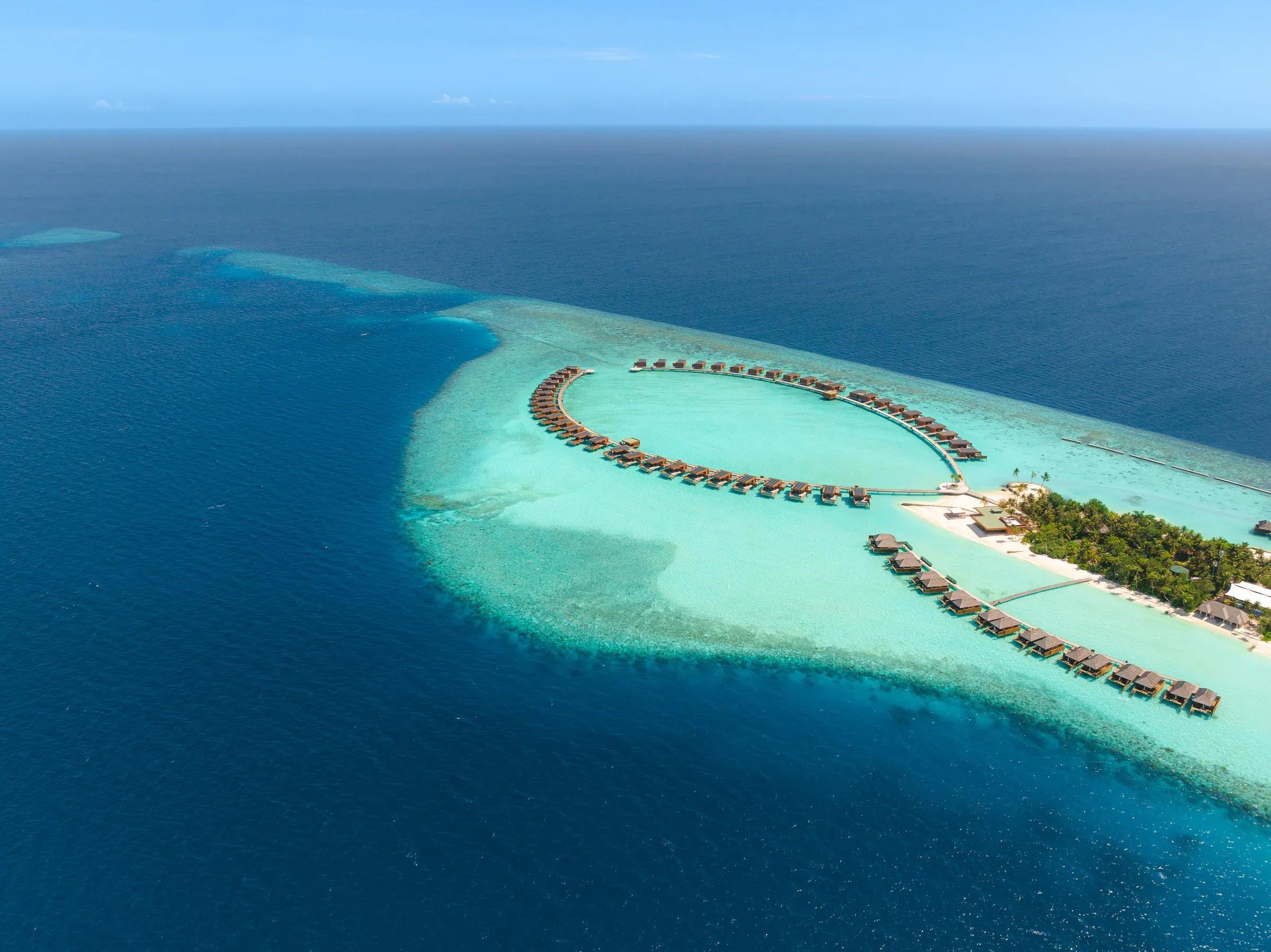 Vista aerea di ville sull'acqua e laguna turchese al Veligandu Island Resort & Spa alle Maldive.