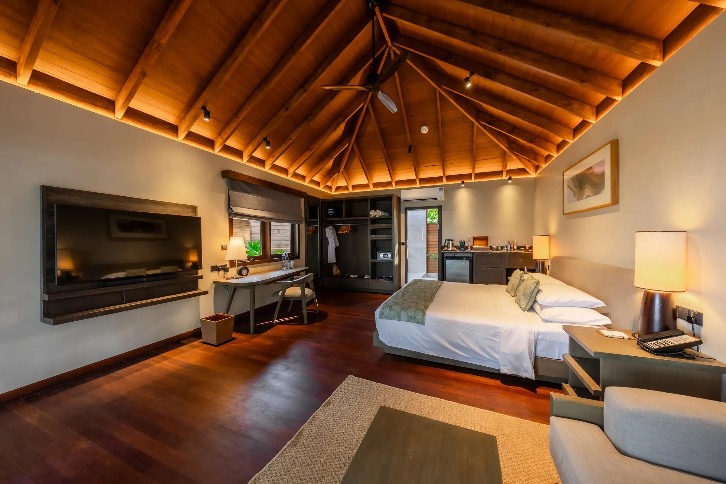 Interno della Beach Villa con letto matrimoniale e soffitto in legno al Veligandu Island Resort & Spa.