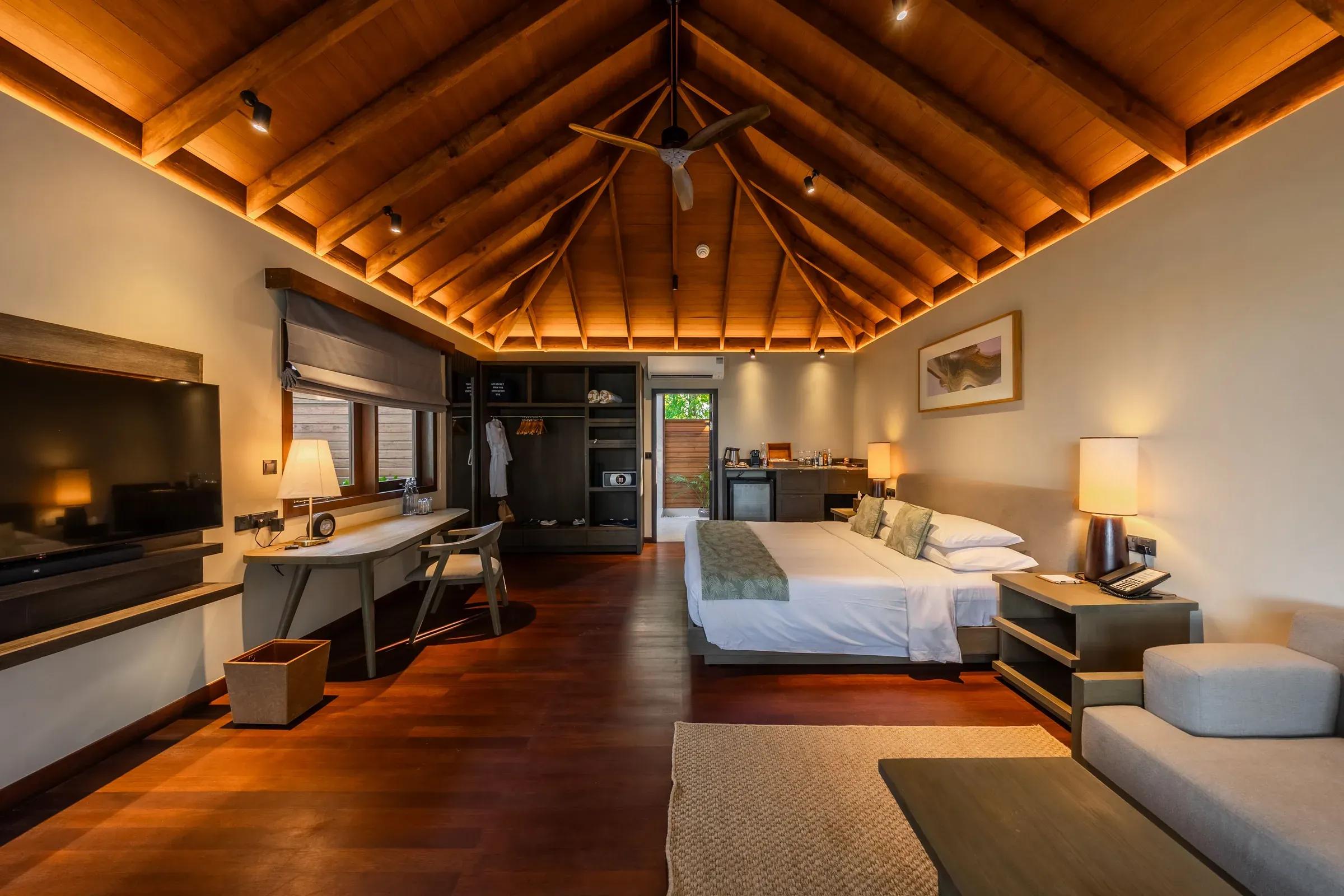 Interno della Beach Villa con soffitto in legno e letto king size al Veligandu Island Resort & Spa.