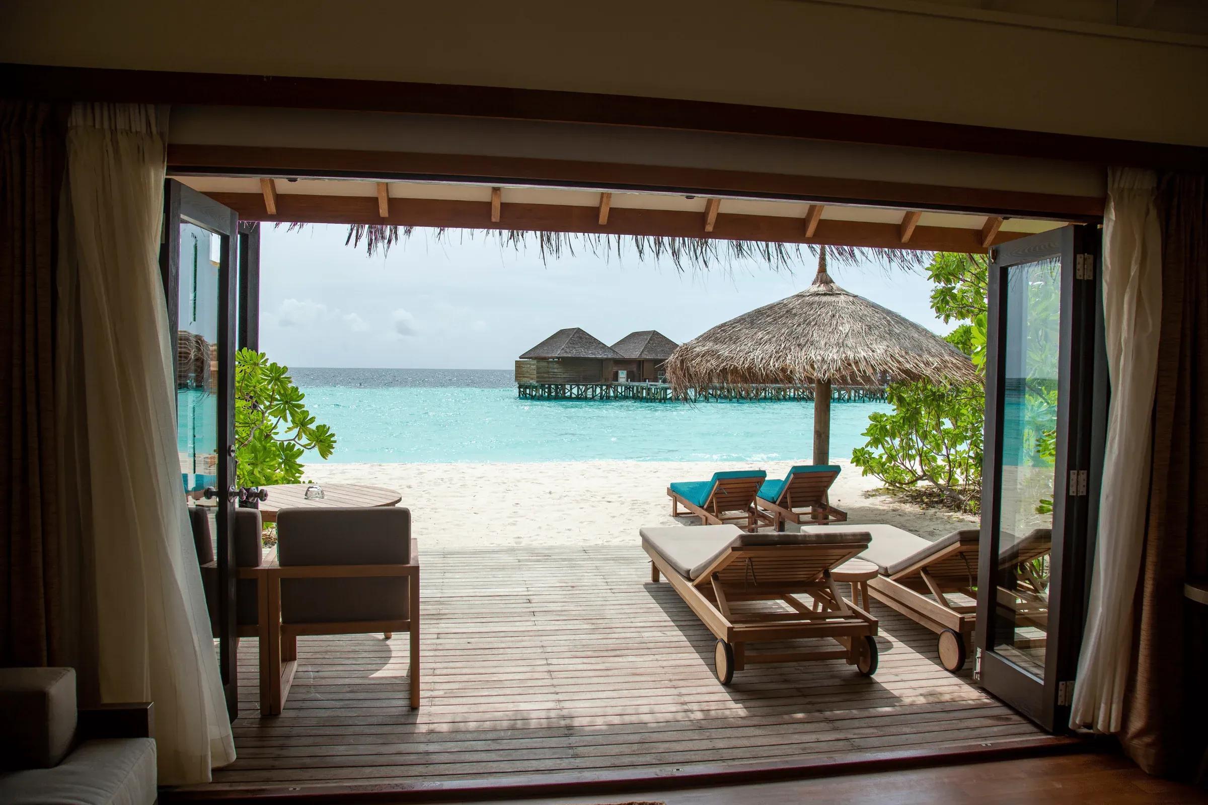 Terrazza della Jacuzzi Beach Villa con lettini in legno e vista mare al Veligandu Island Resort & Spa.