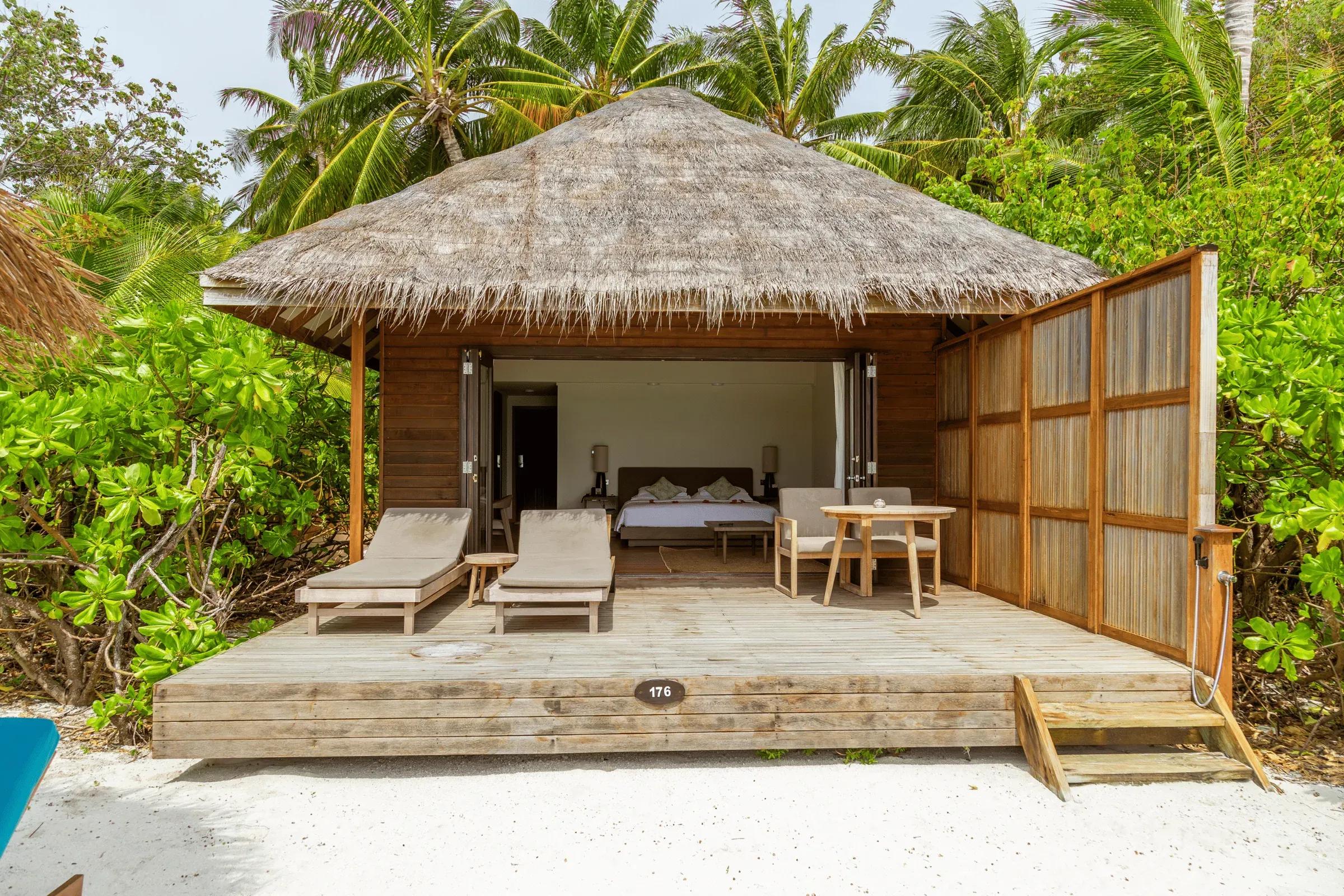 Terrazza della Jacuzzi Beach Villa con lettini e tavolo su piattaforma di legno presso Veligandu Island Resort & Spa.