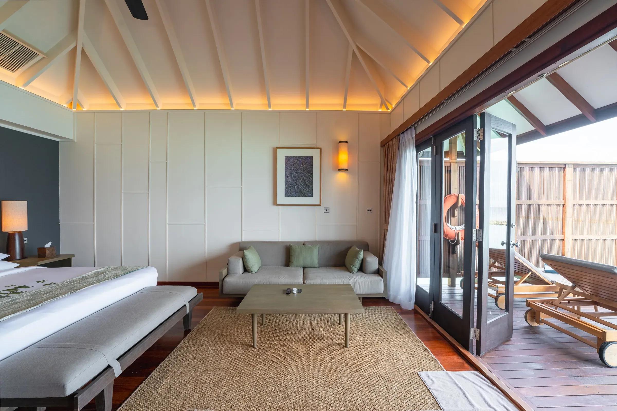 Interno della Ocean Jacuzzi Villa con divano, tavolino e accesso alla terrazza nel Veligandu Island Resort & Spa.