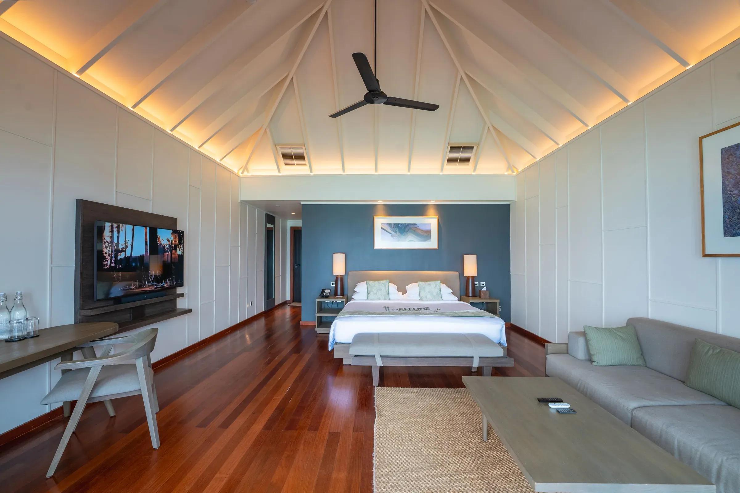 Interno della Ocean Jacuzzi Villa con letto king size, divano e TV al Veligandu Island Resort & Spa.